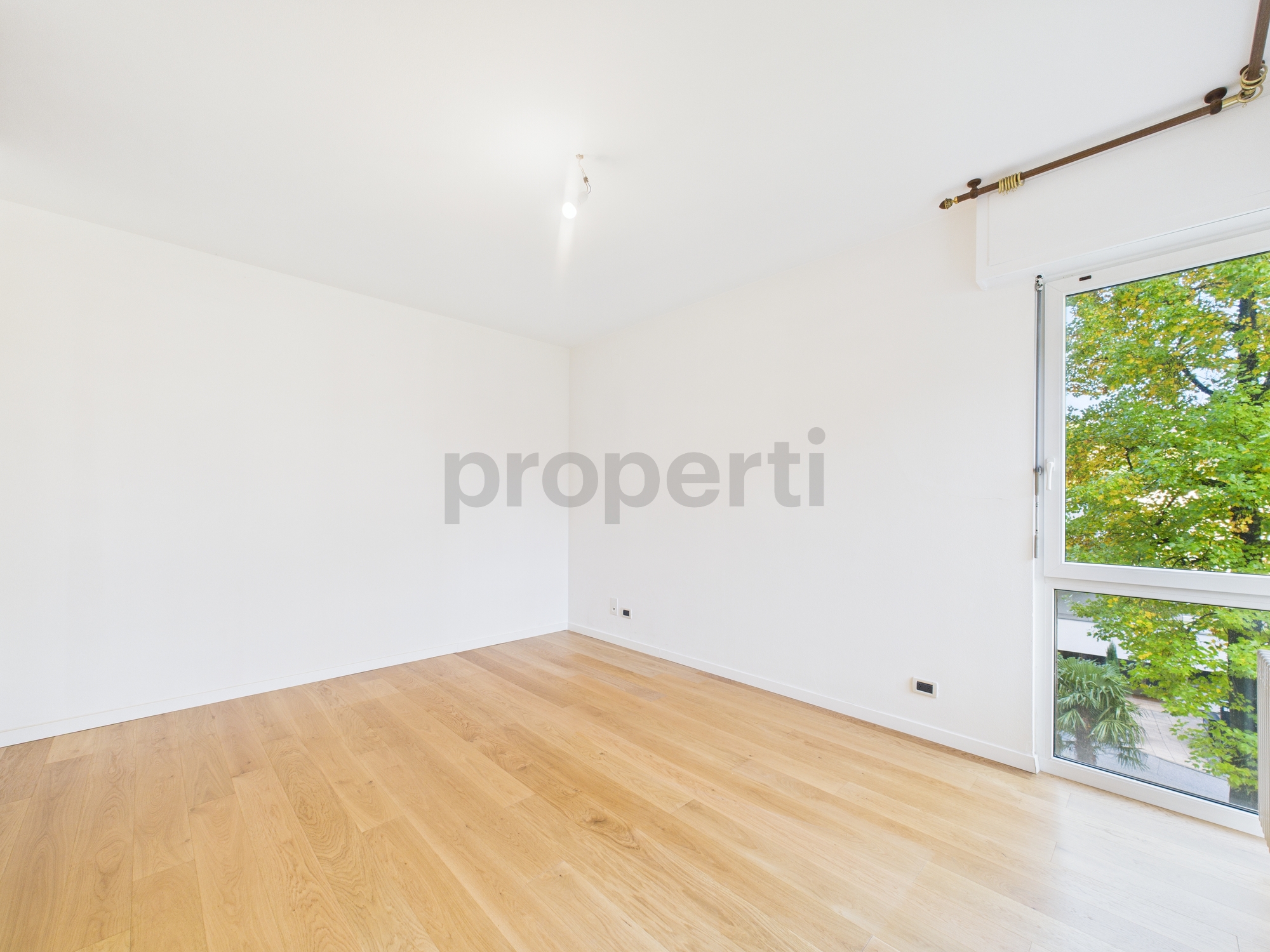 Helles leeres Zimmer mit Parkett und großem Fenster