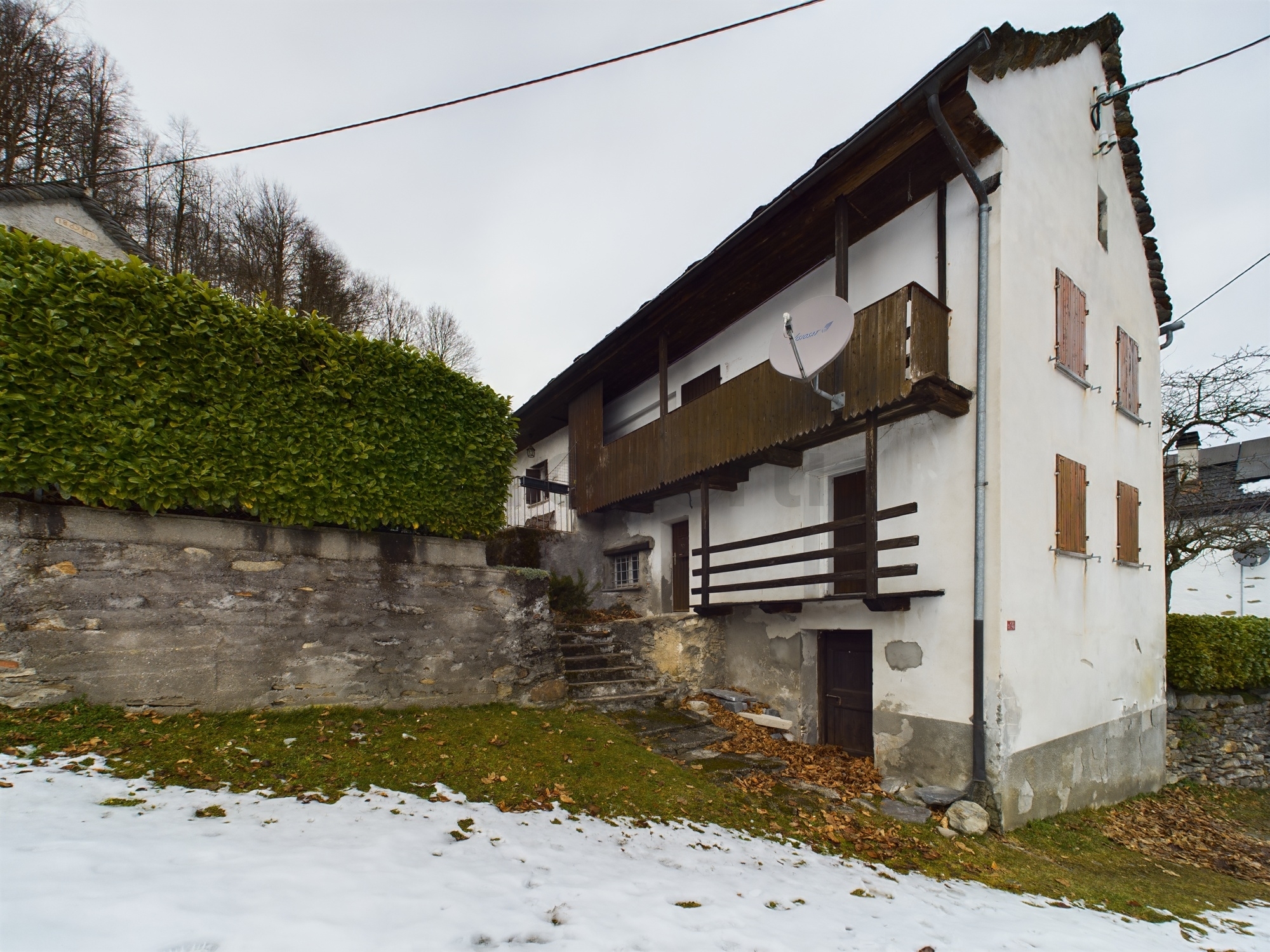 Altes Wohnhaus mit Balkon und schneebedecktem Garten