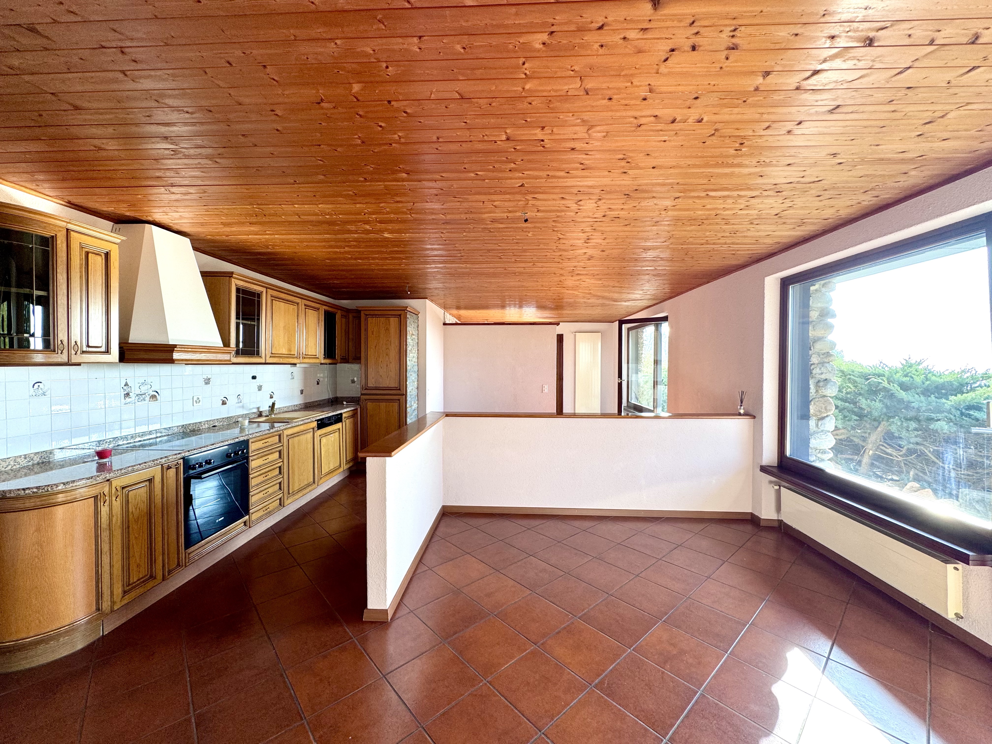 Küche mit Holzdecke und großem Fenster