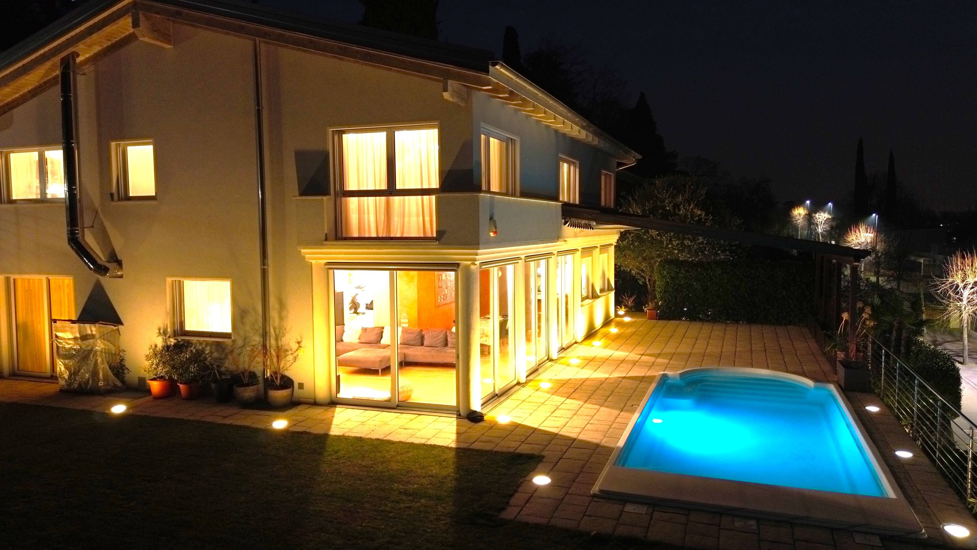 Nachtansicht eines Hauses mit beleuchtetem Pool