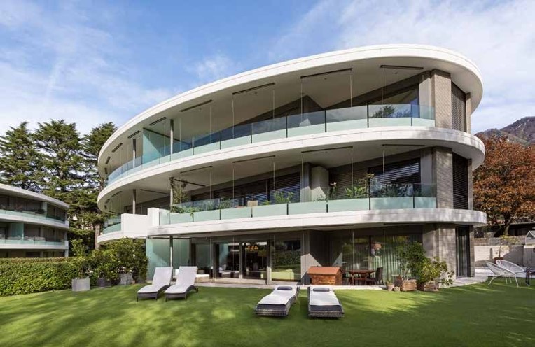 Moderne Villa mit geschwungenen Balkonen und großer Rasenfläche