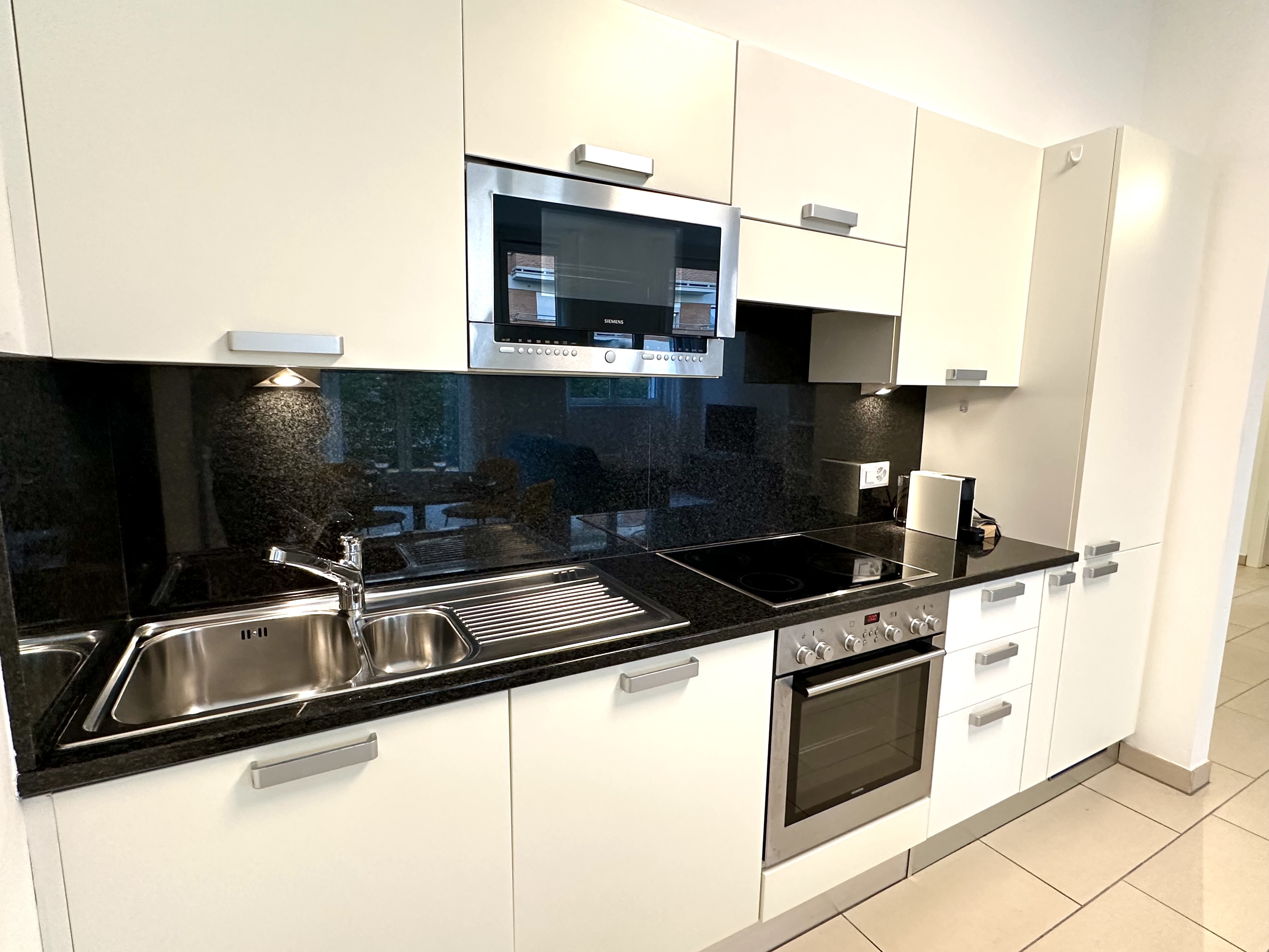 Moderne Einbauküche mit hellen Fronten und schwarzen Arbeitsflächen