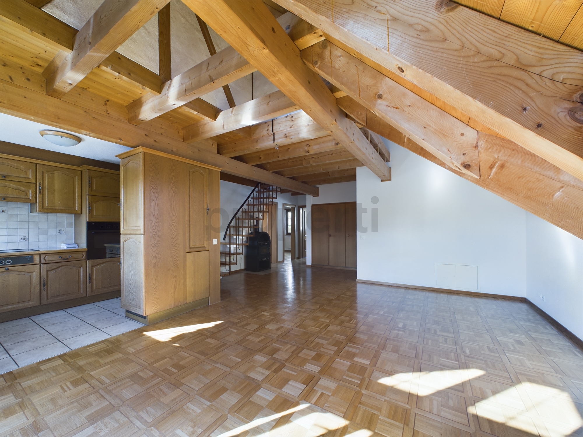 Wohnraum mit offener Küche und sichtbarer Holzbalkendecke