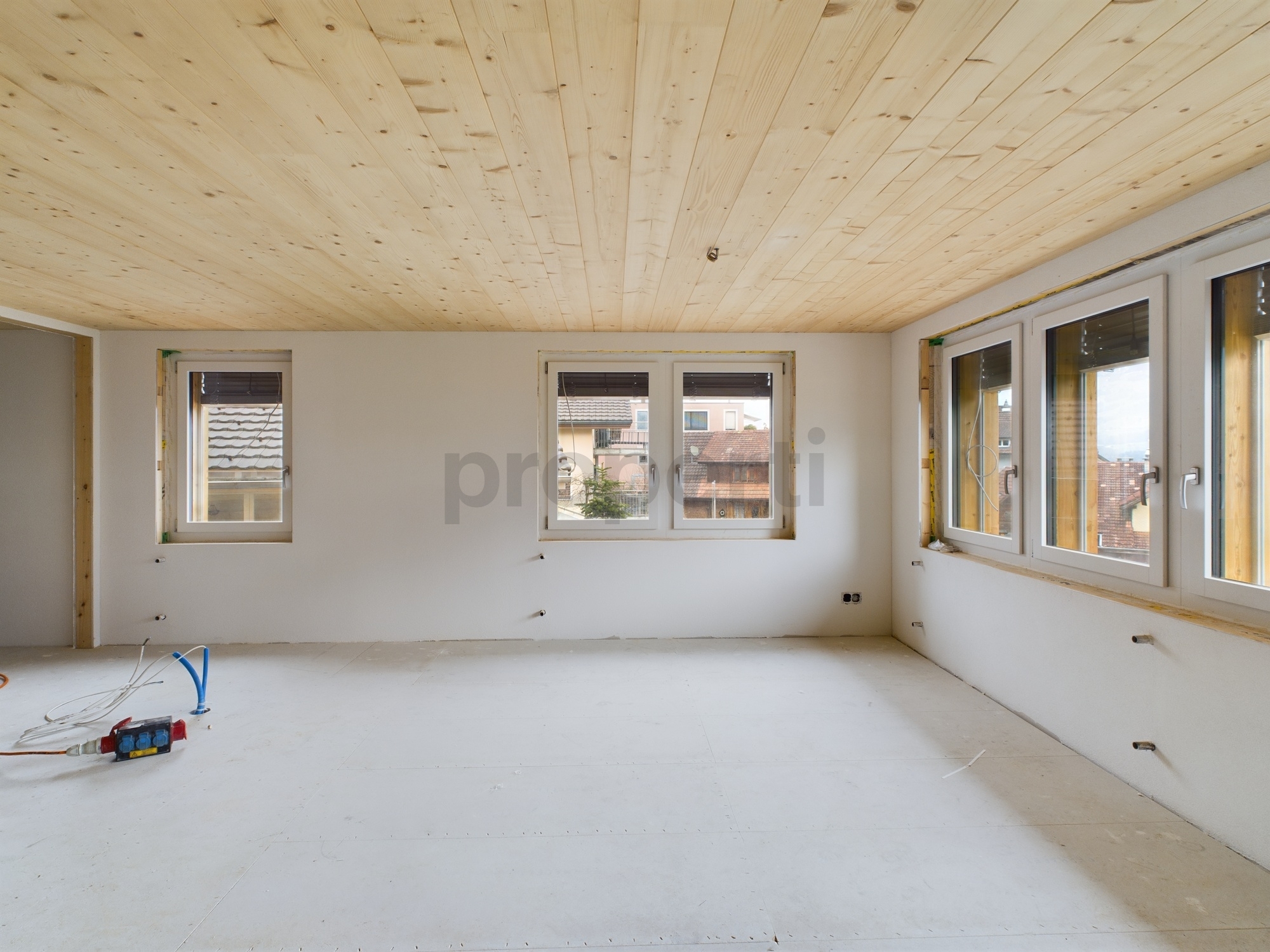 Unfertiger heller Raum mit Holzdecke und mehreren Fenstern