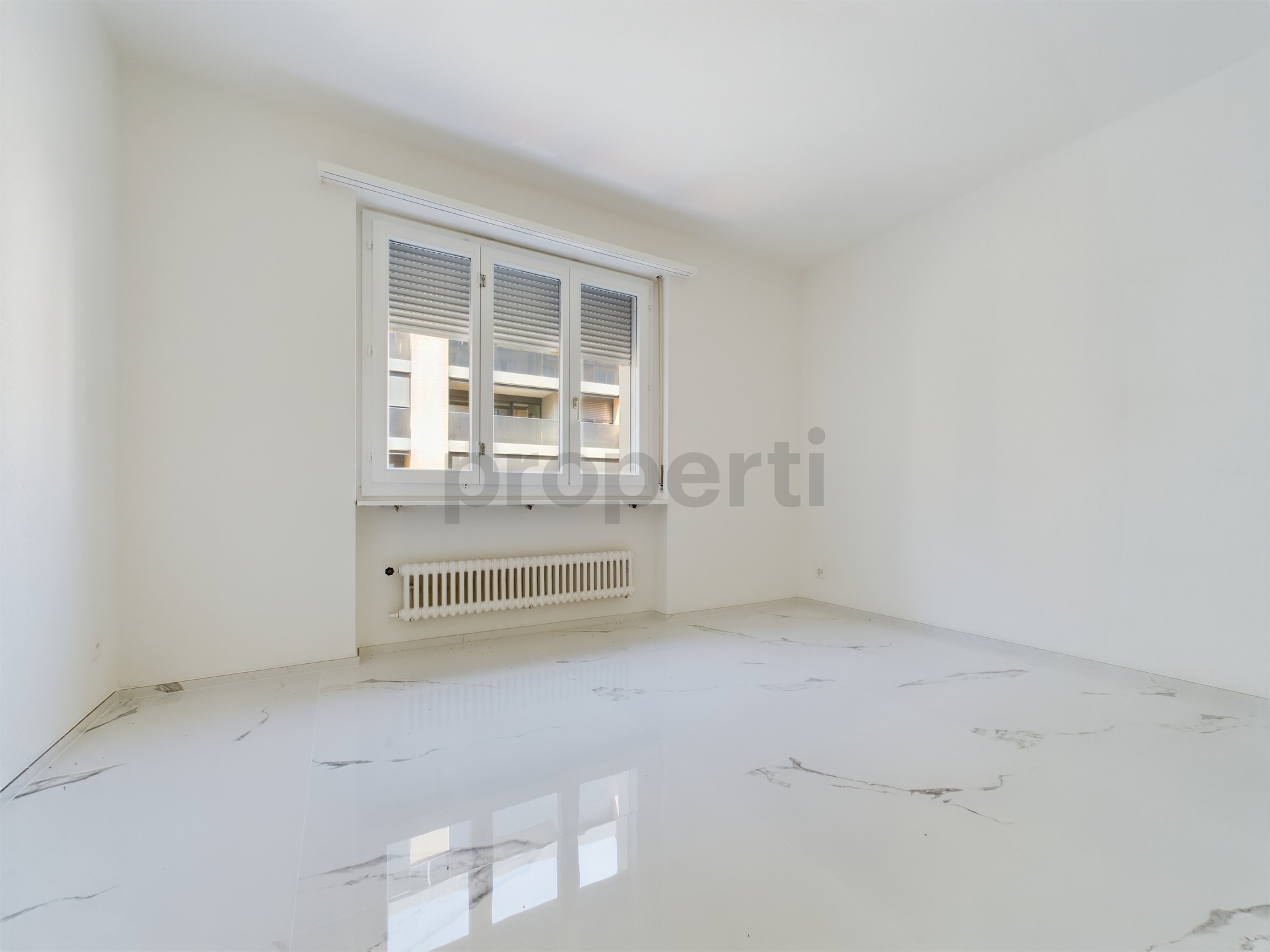 Leerer heller Raum mit Fenster und Heizkörper