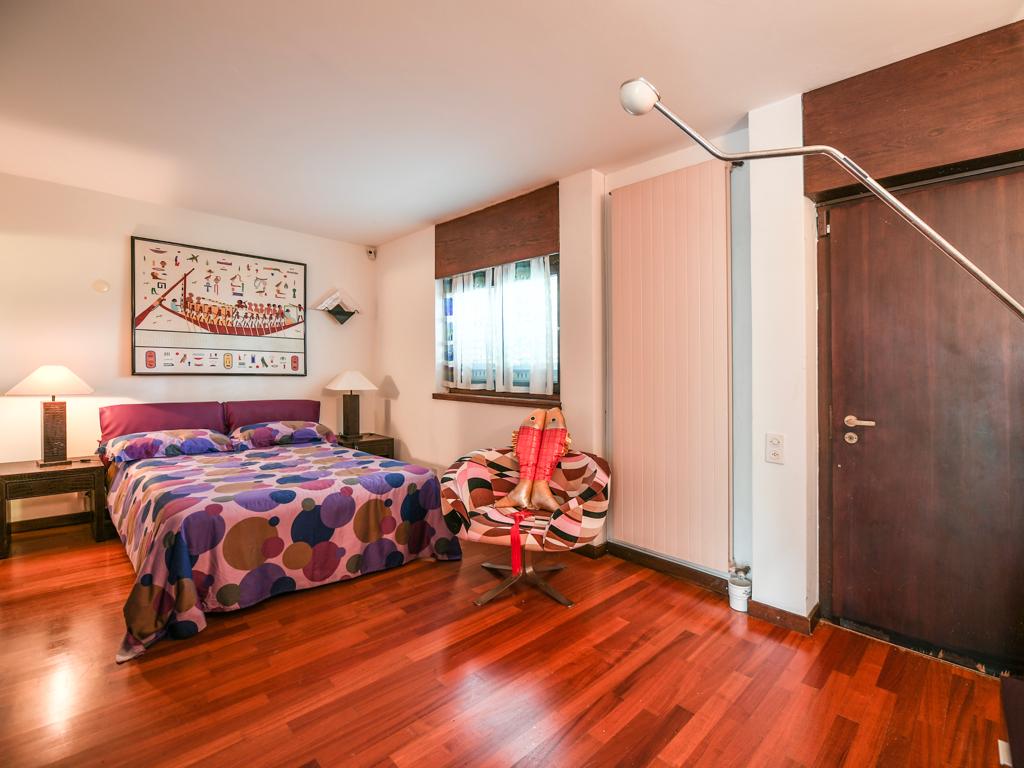 Schlafzimmer mit warmem Parkett und farbigem Bettbezug