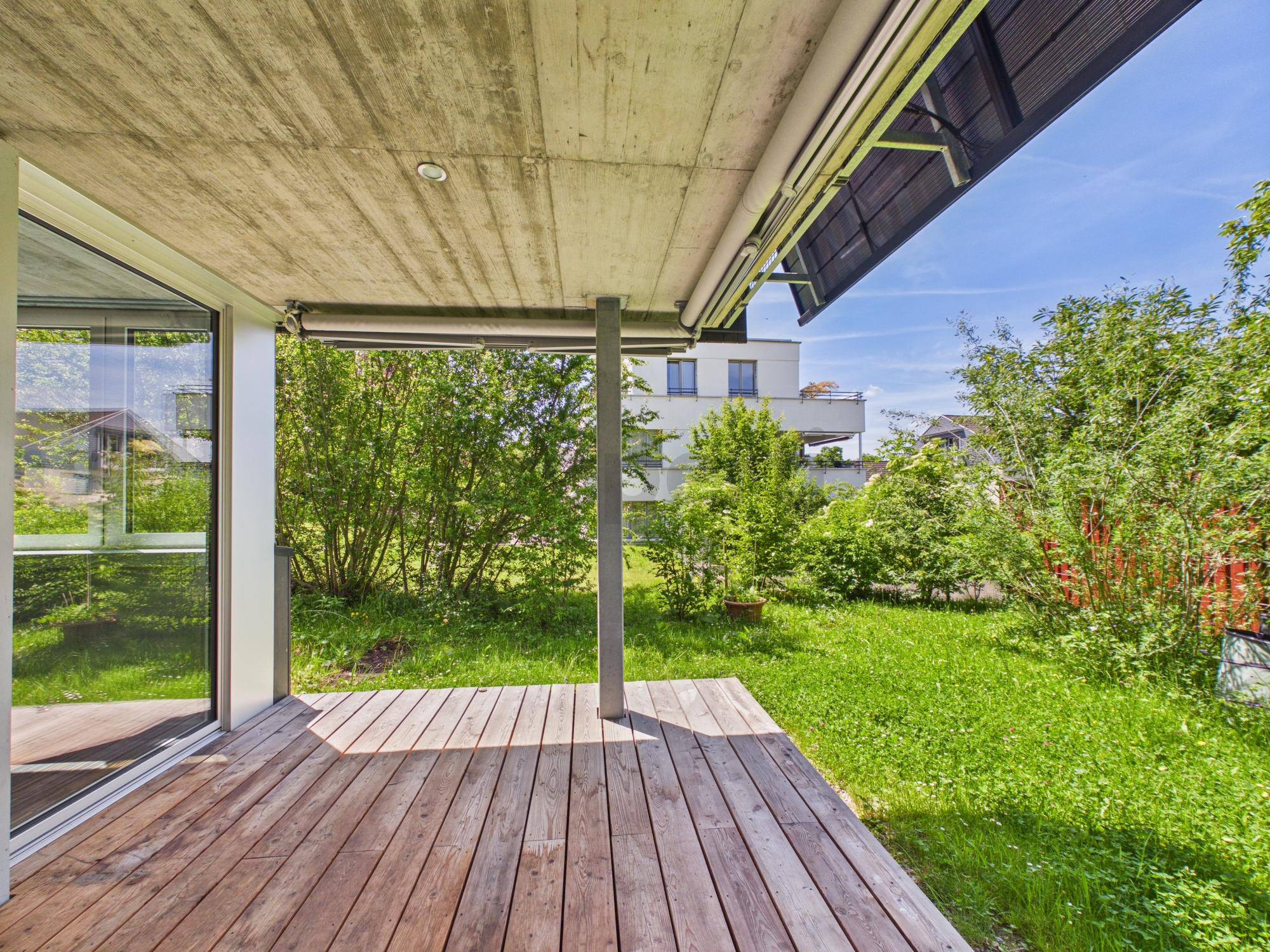 Überdachte Holzterrasse mit Gartenblick