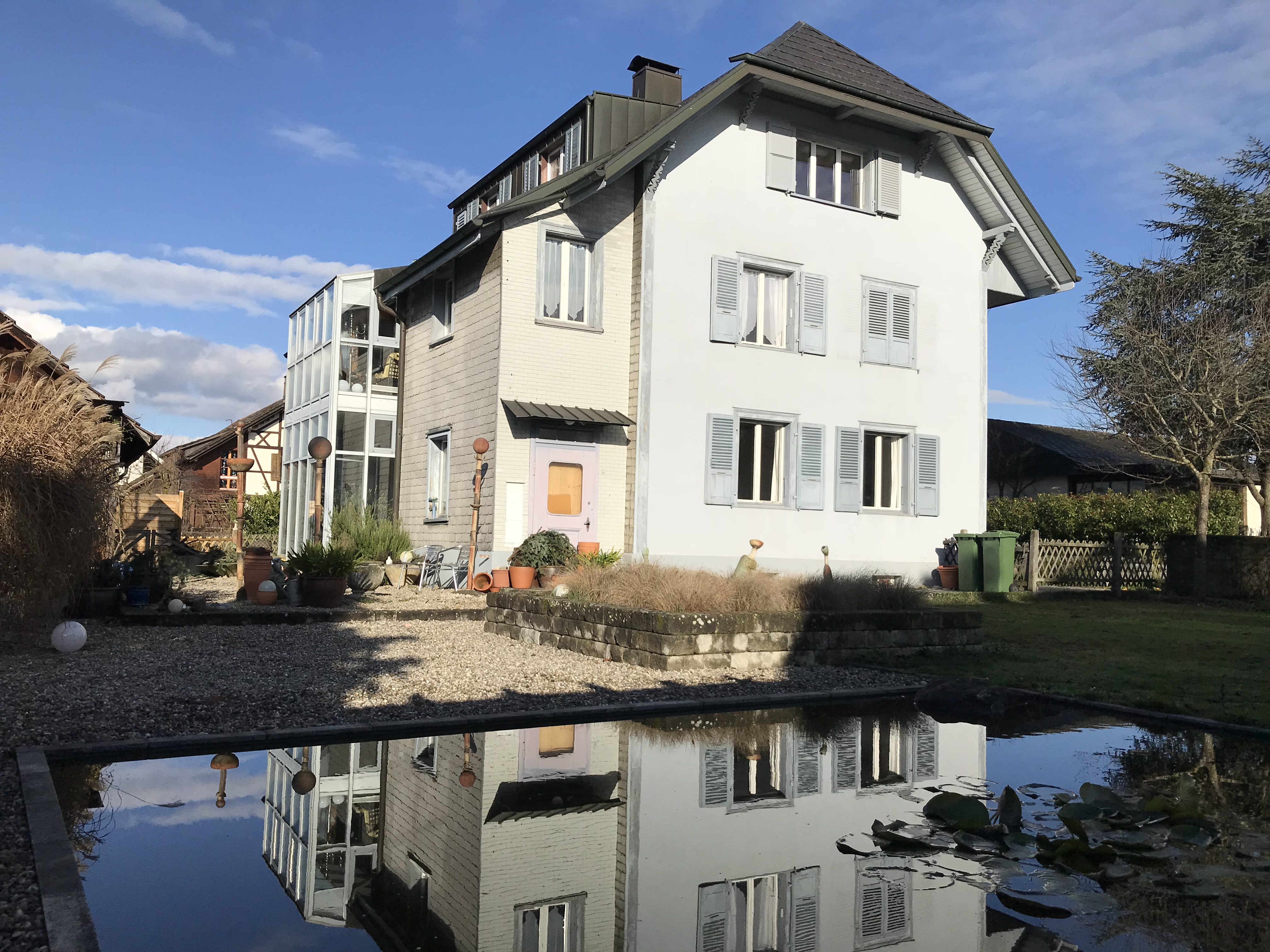 Außenansicht eines Einfamilienhauses mit Garten und Wasserbecken