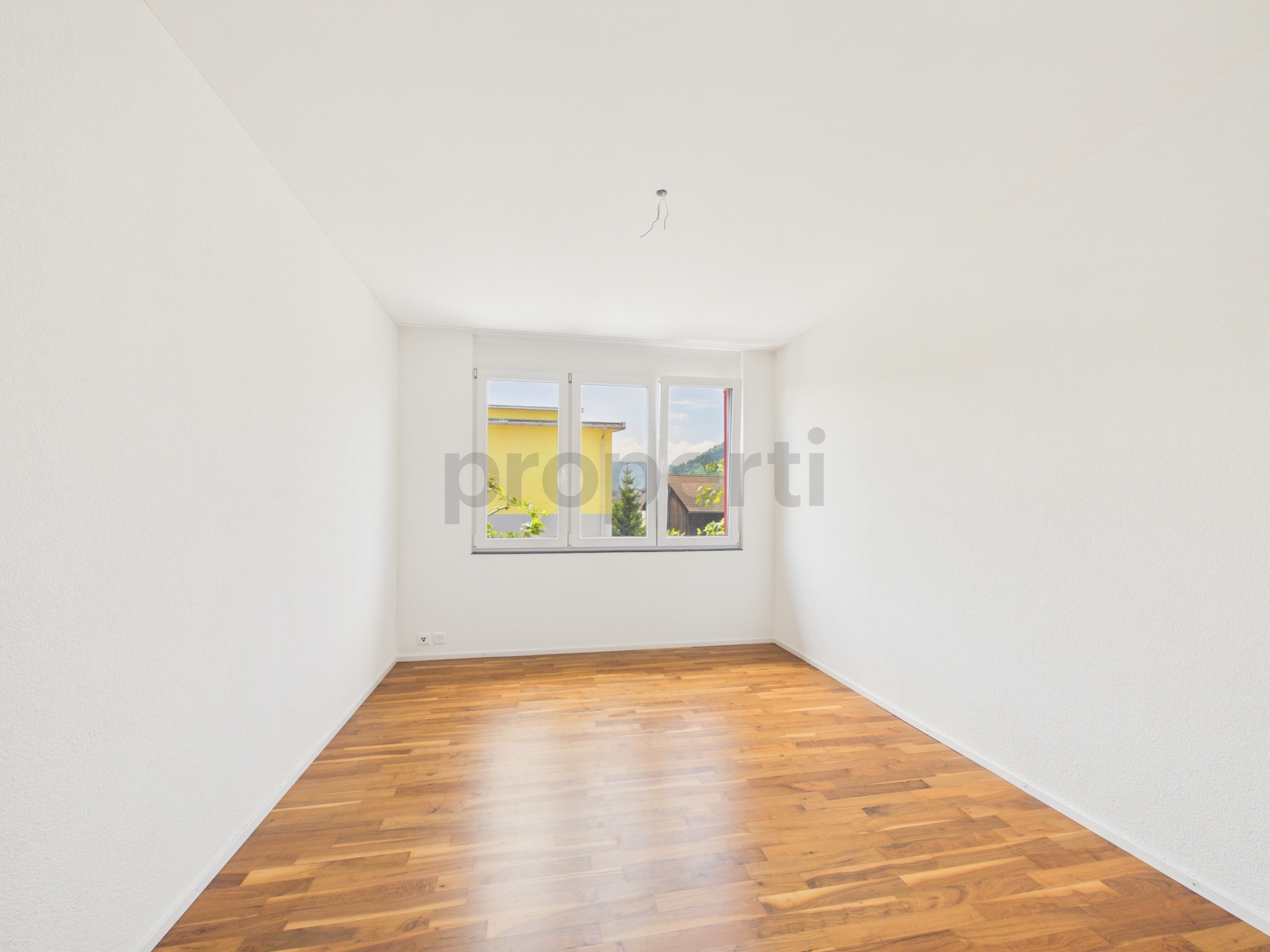 Heller leerer Raum mit Parkettboden und Fenster