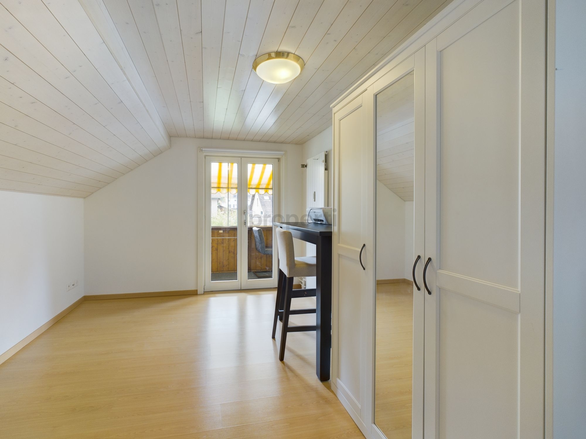 Heller Dachraum mit Kleiderschrank und Balkonzugang