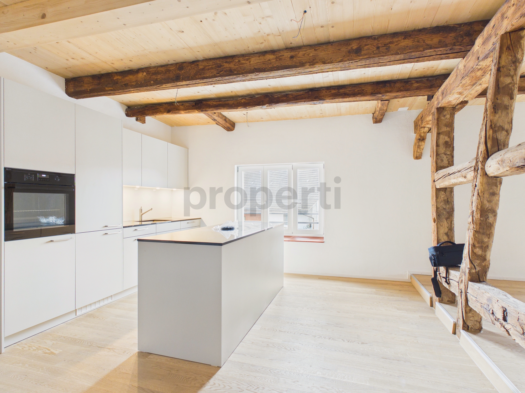 Helle, moderne Küche mit Holzbalken und Kochinsel