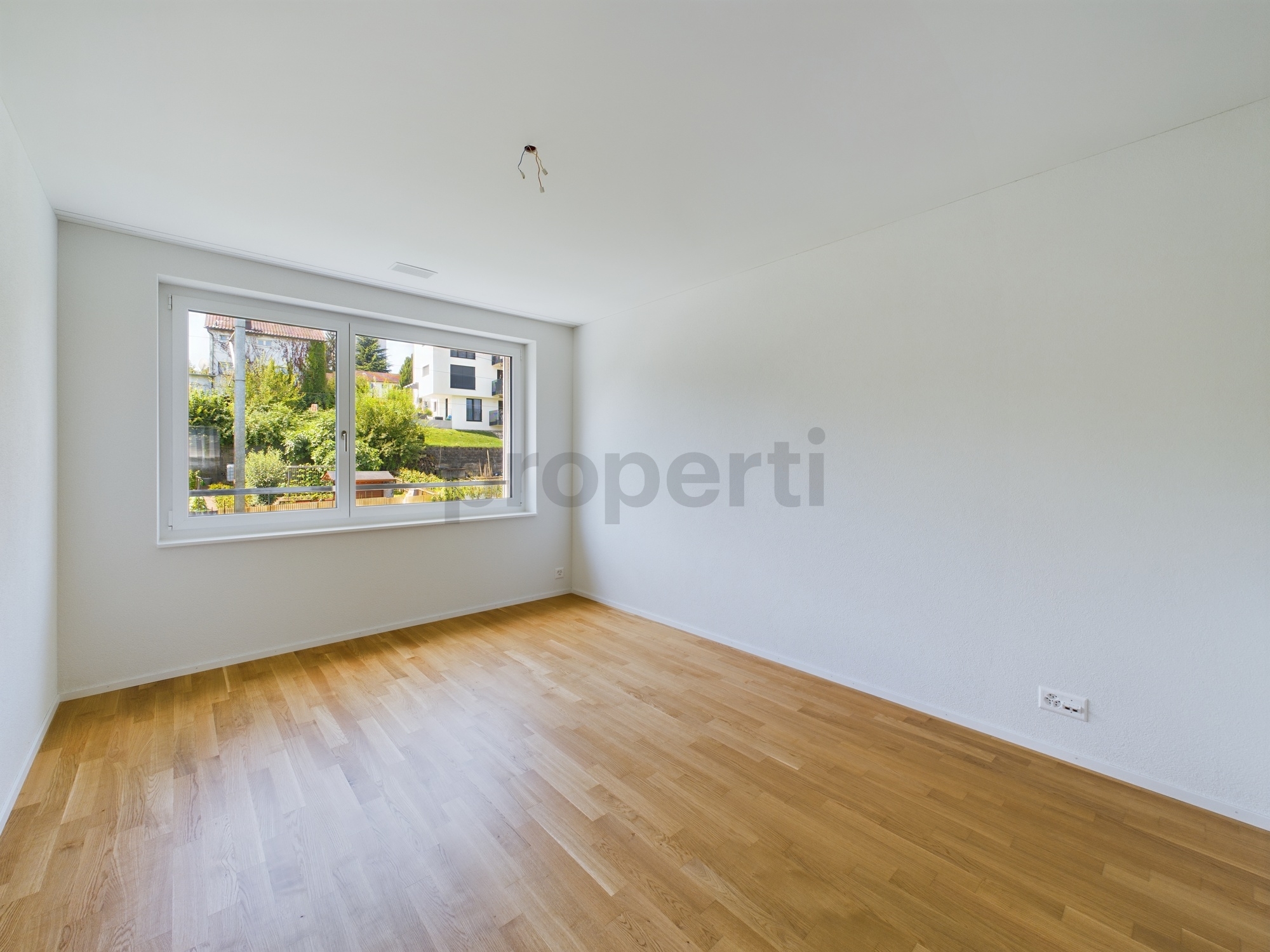Leerer, heller Raum mit Parkett und Fenster