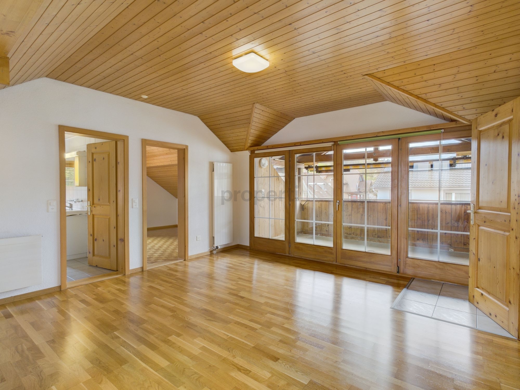 Heller Wohnraum mit Holzdecke und Balkonzugang