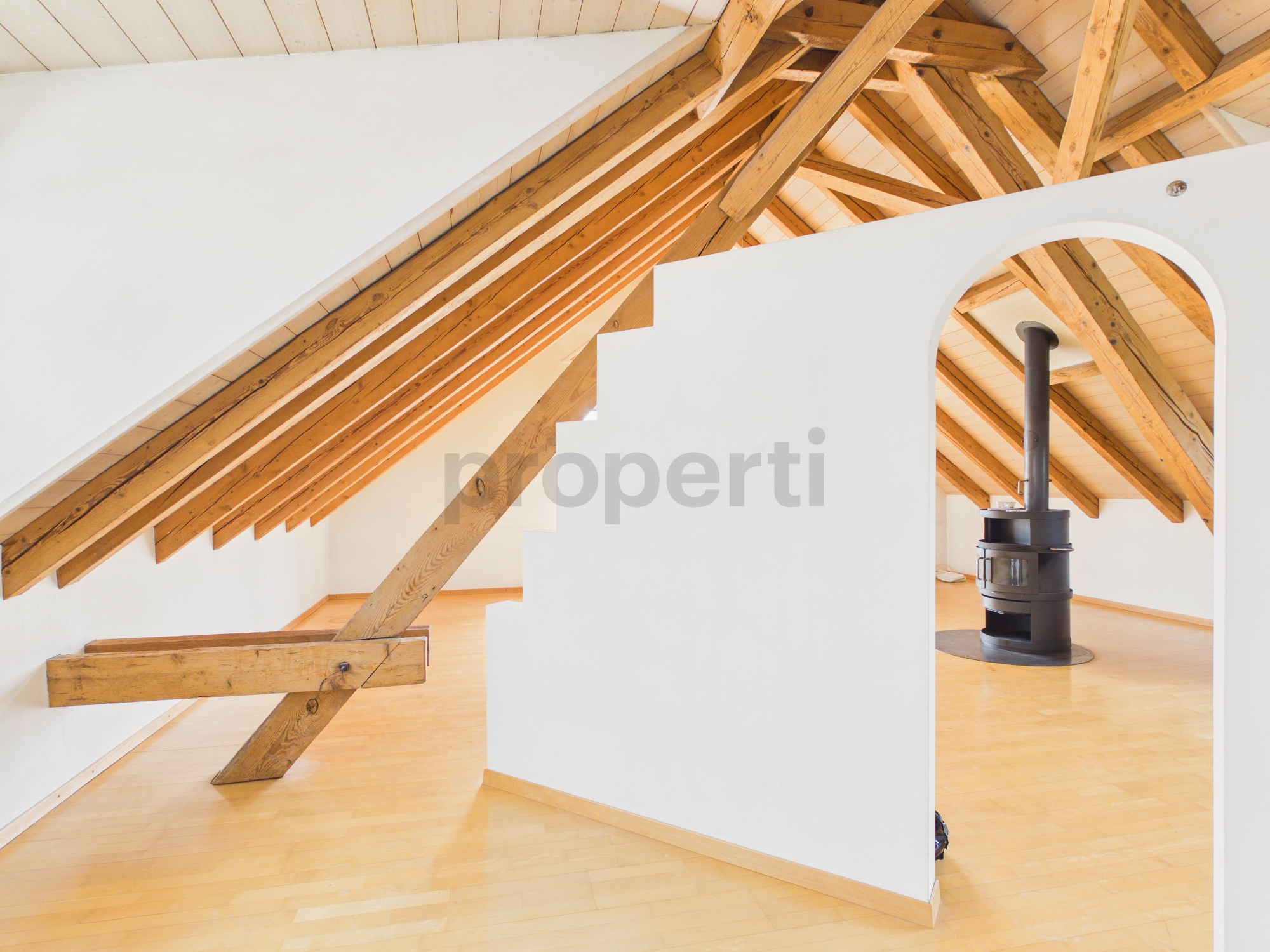Ausgebauter Dachraum mit Sichtbalken und Kaminofen