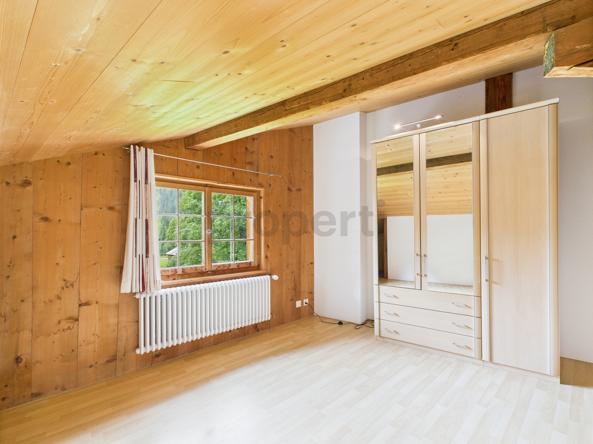 Gemütliches Schlafzimmer mit Holzvertäfelung und Dachschräge