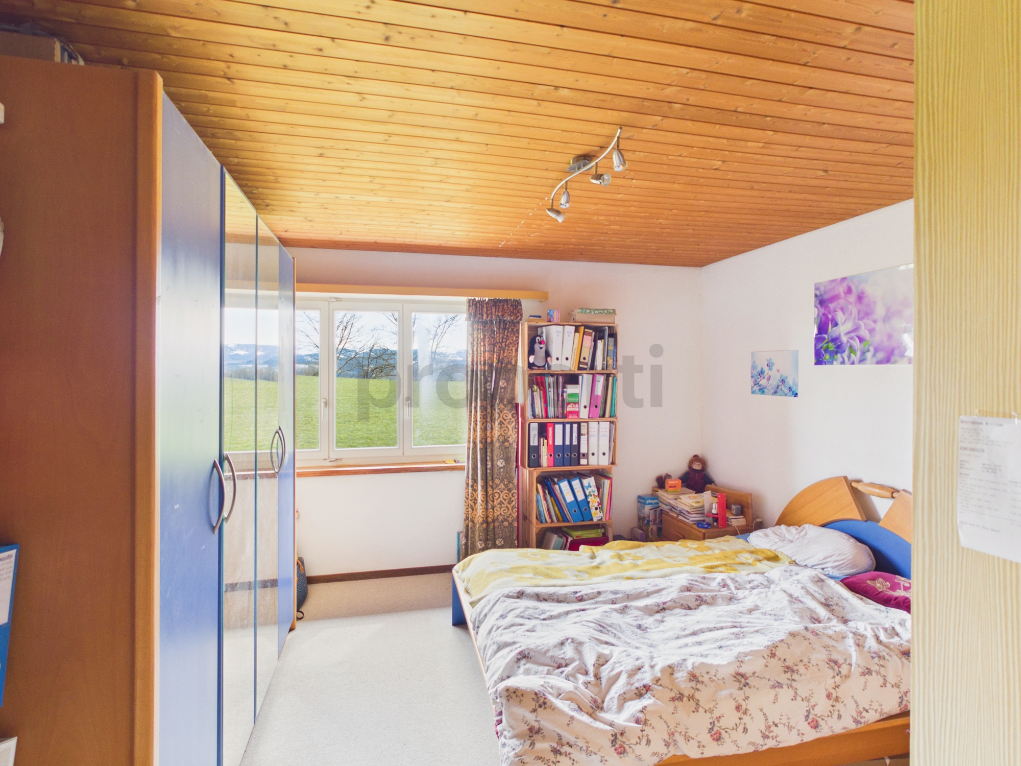 Gemütliches Schlafzimmer mit Holzdecke und Blick ins Grüne