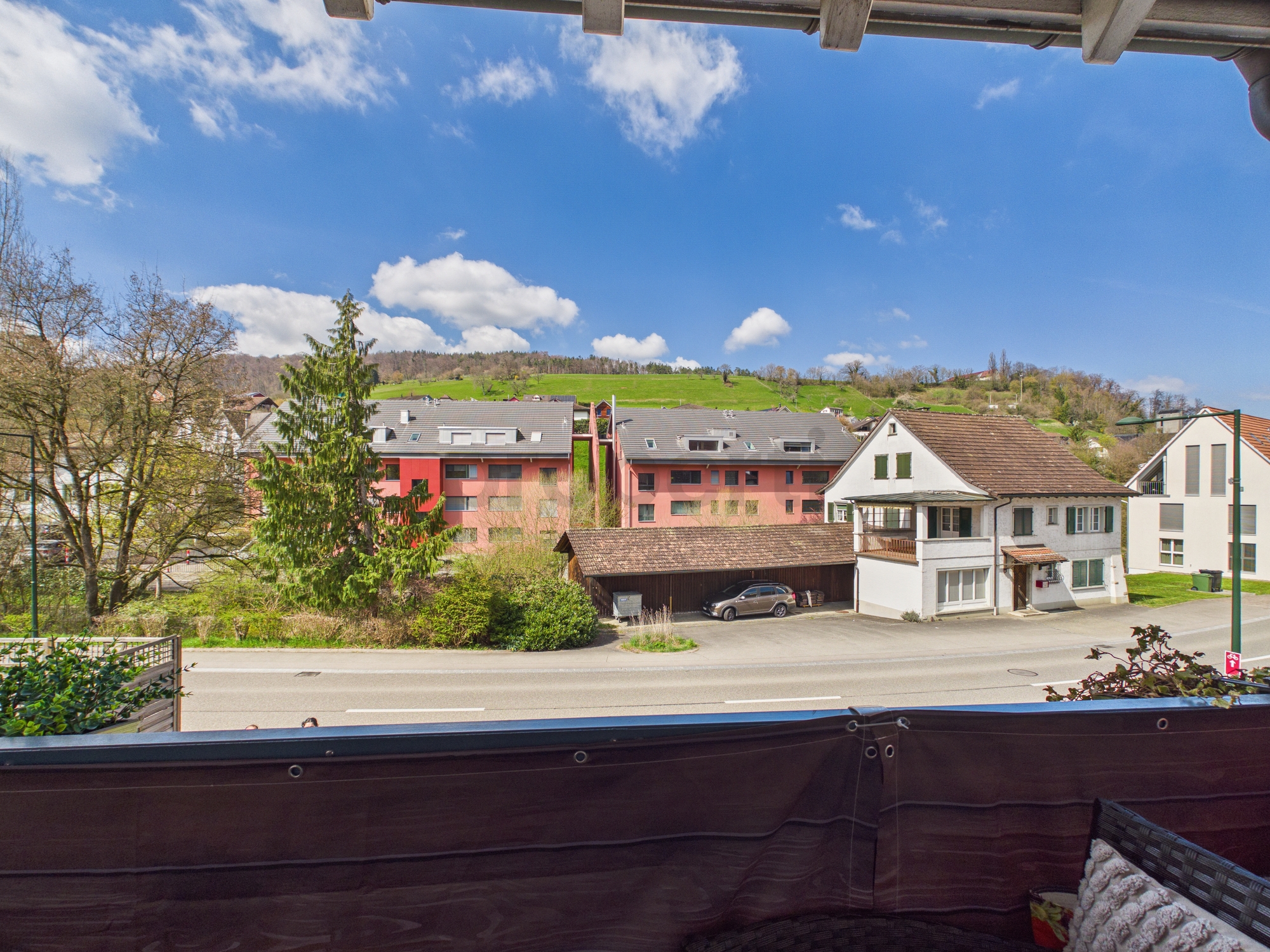 Blick vom Balkon auf Wohnhäuser und Hügellandschaft
