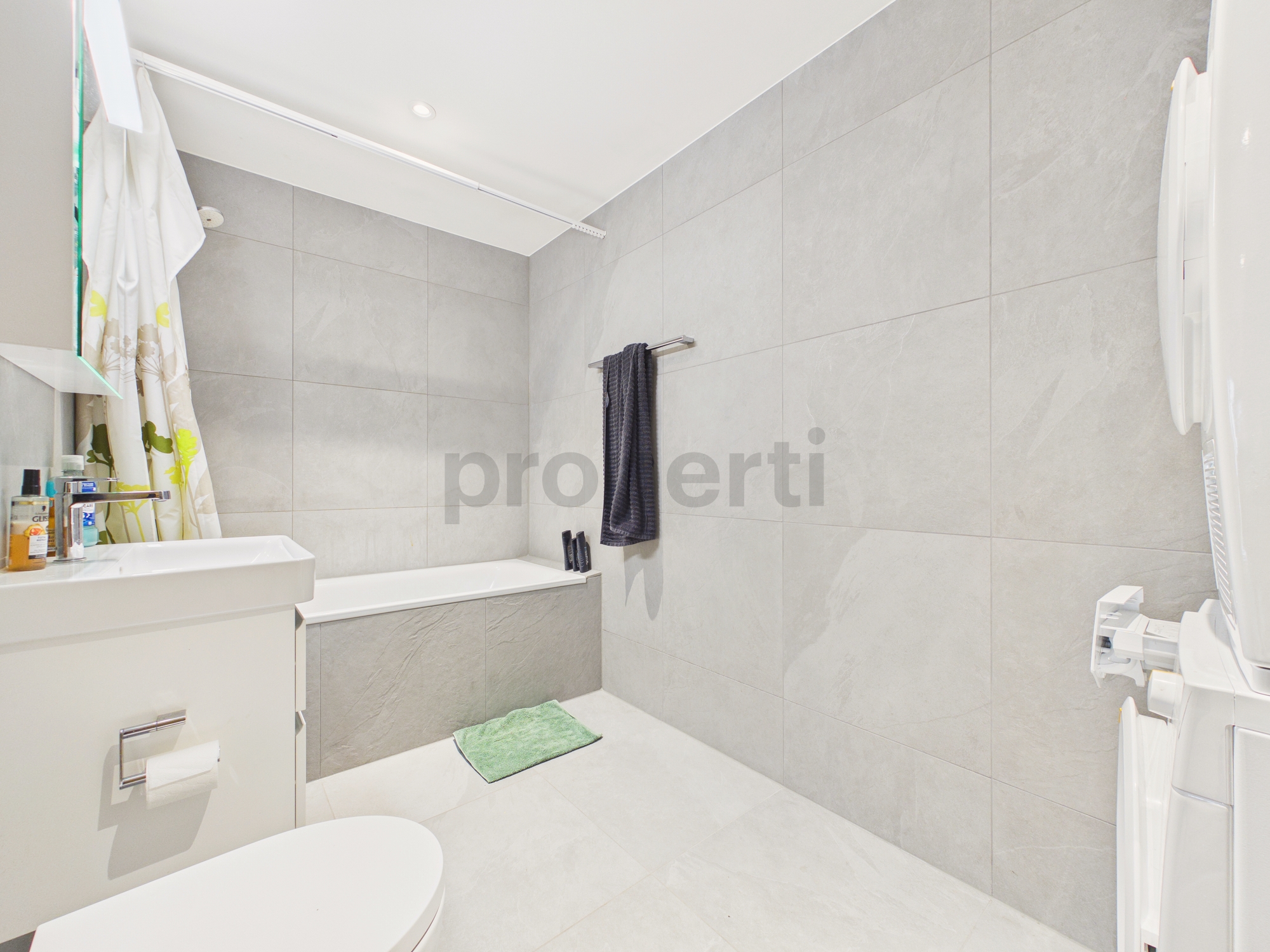 Modernes Badezimmer mit heller, großformatiger Wandverkleidung