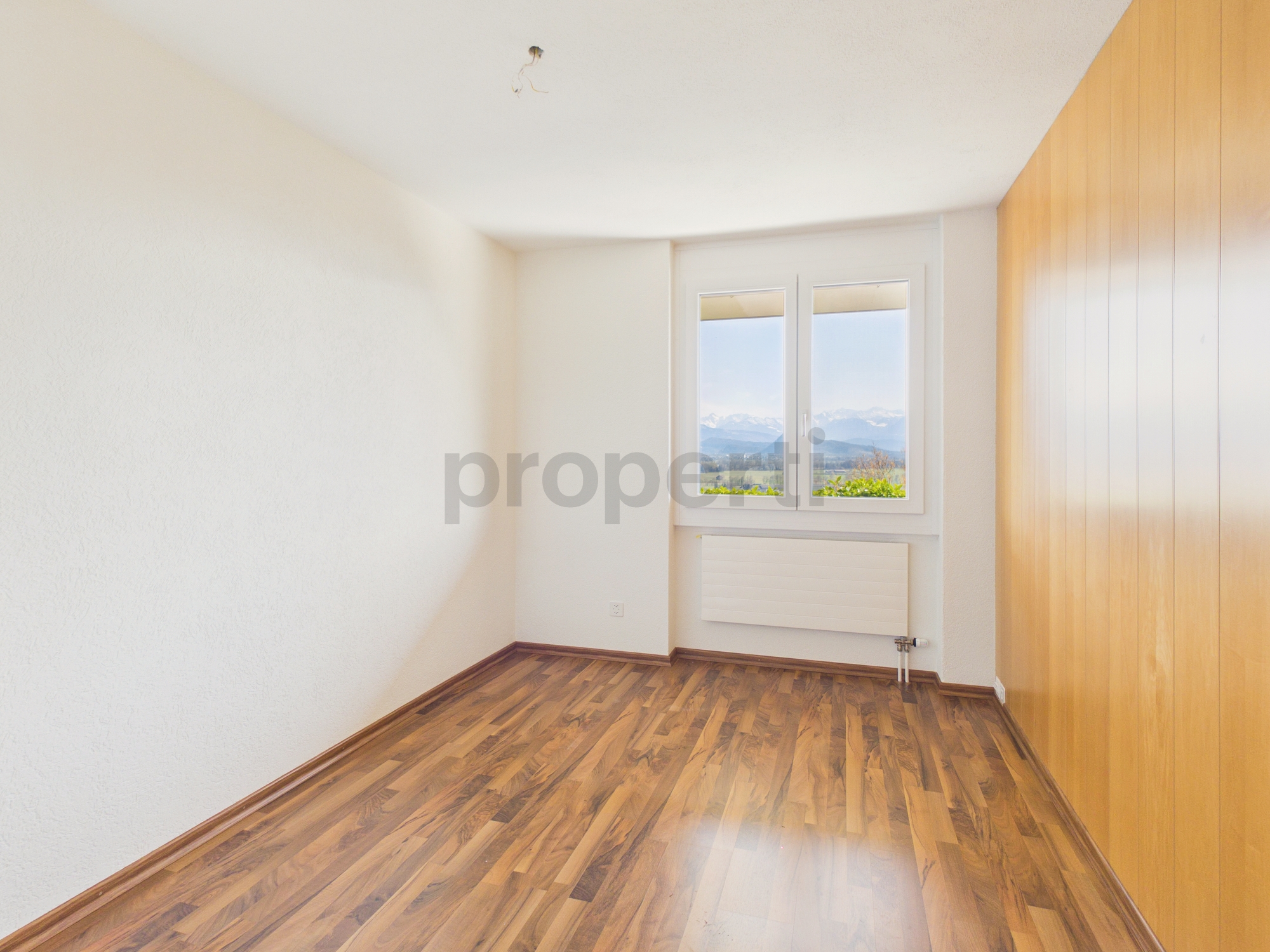 Helles leeres Zimmer mit Holzfußboden und Fensterblick
