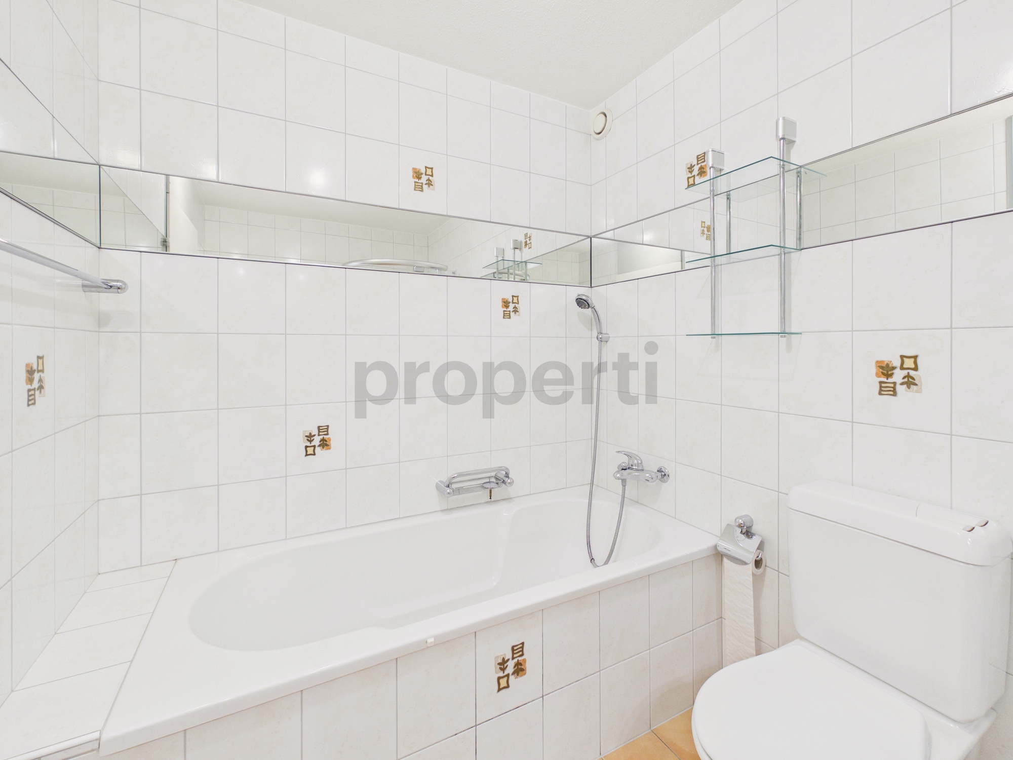 Kleines weiß gefliestes Badezimmer mit Wanne und WC