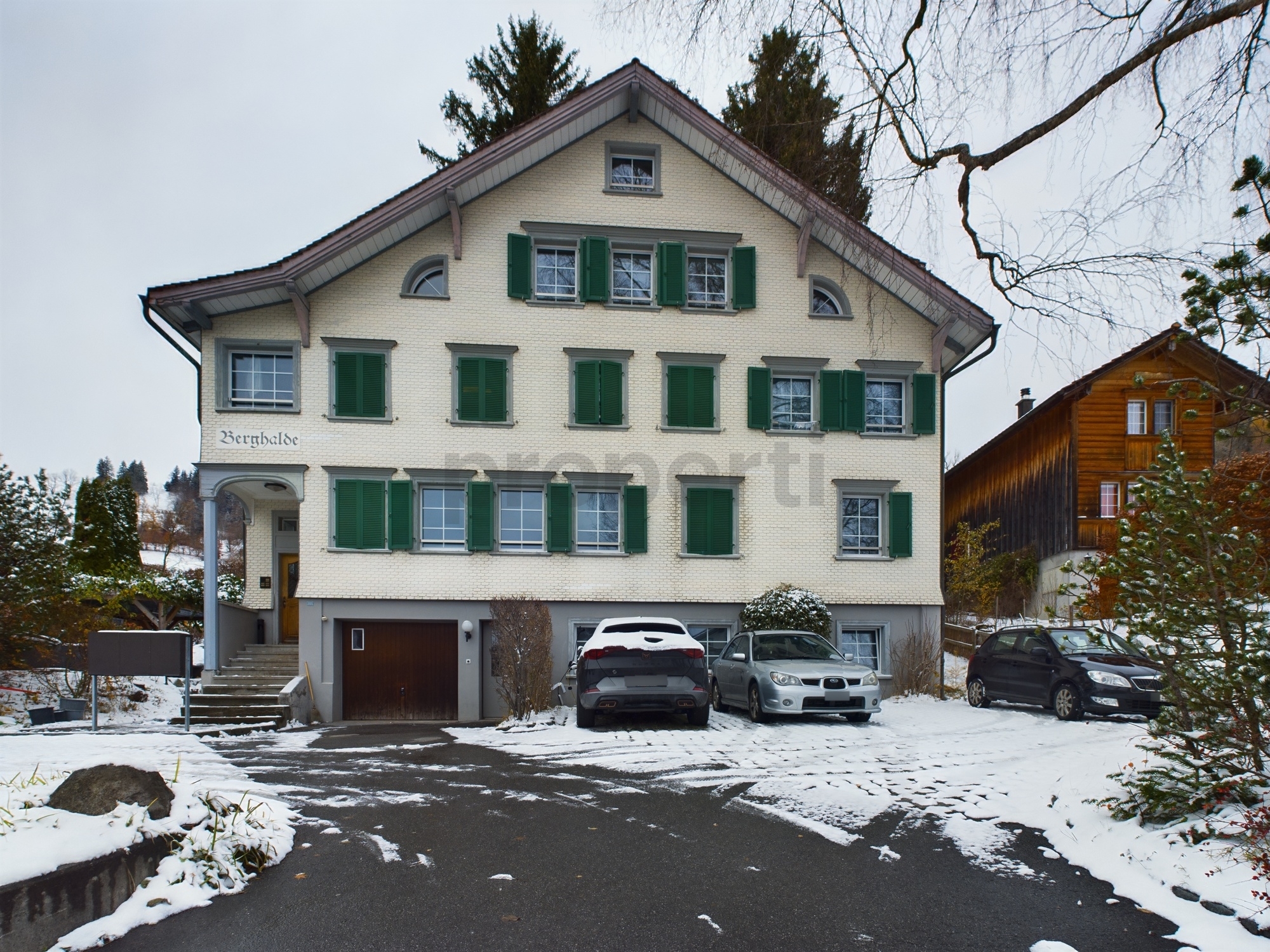 Alpines Mehrfamilienhaus mit Schnee vor dem Eingang