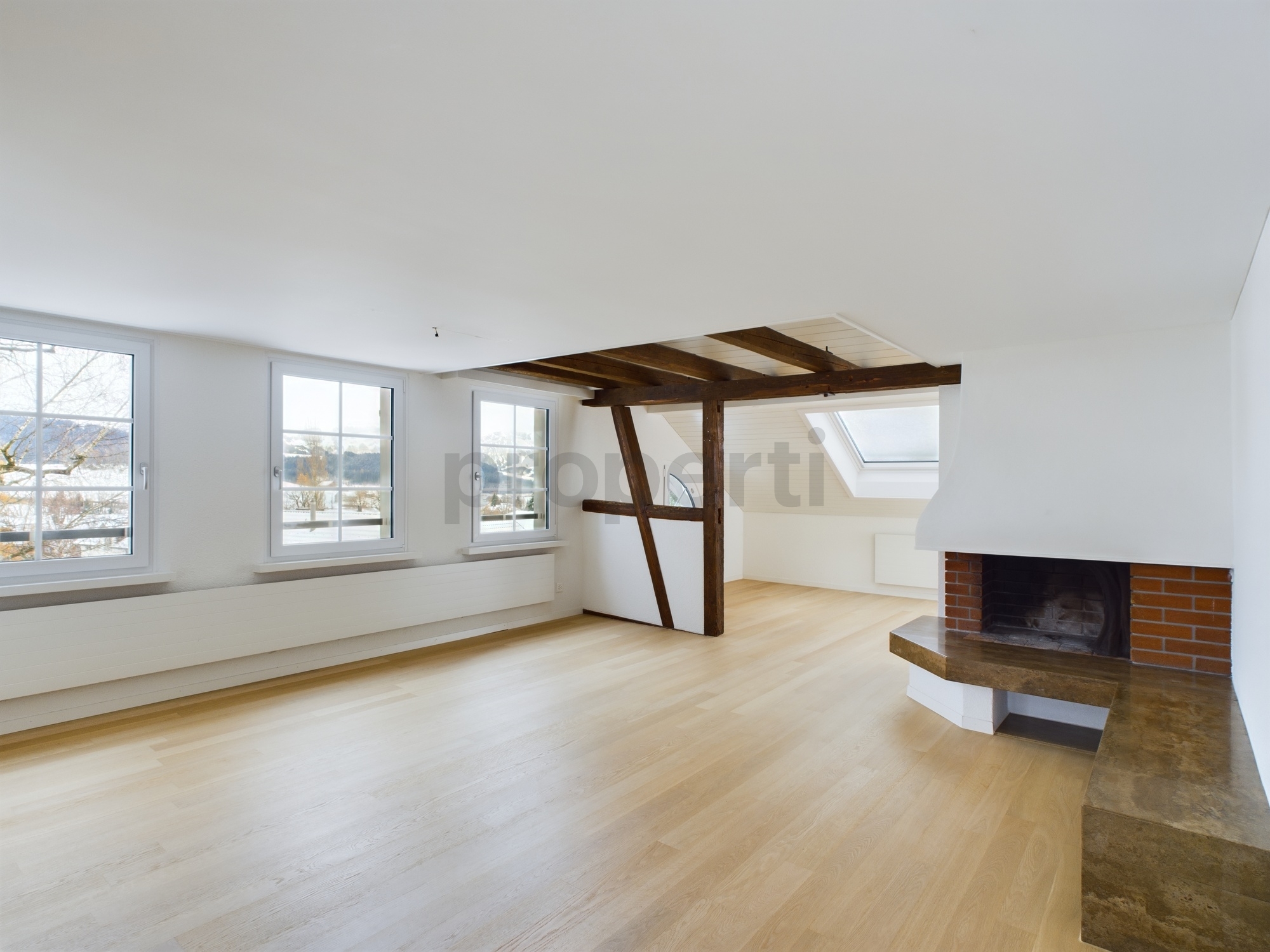 Heller Wohnraum mit Kamin und sichtbaren Holzbalken