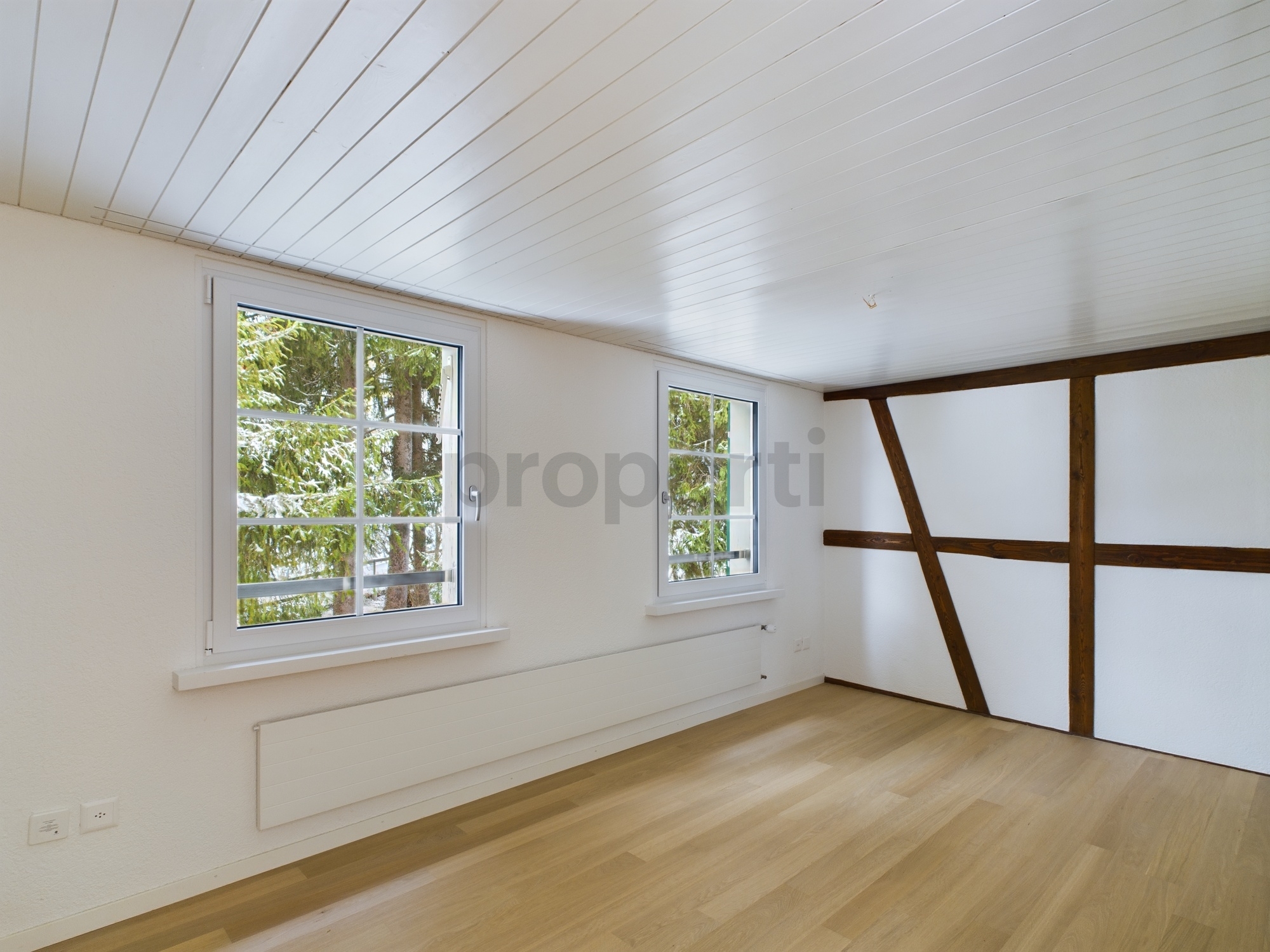 Heller leerer Raum mit Holzfußboden und sichtbarer Balkenkonstruktion