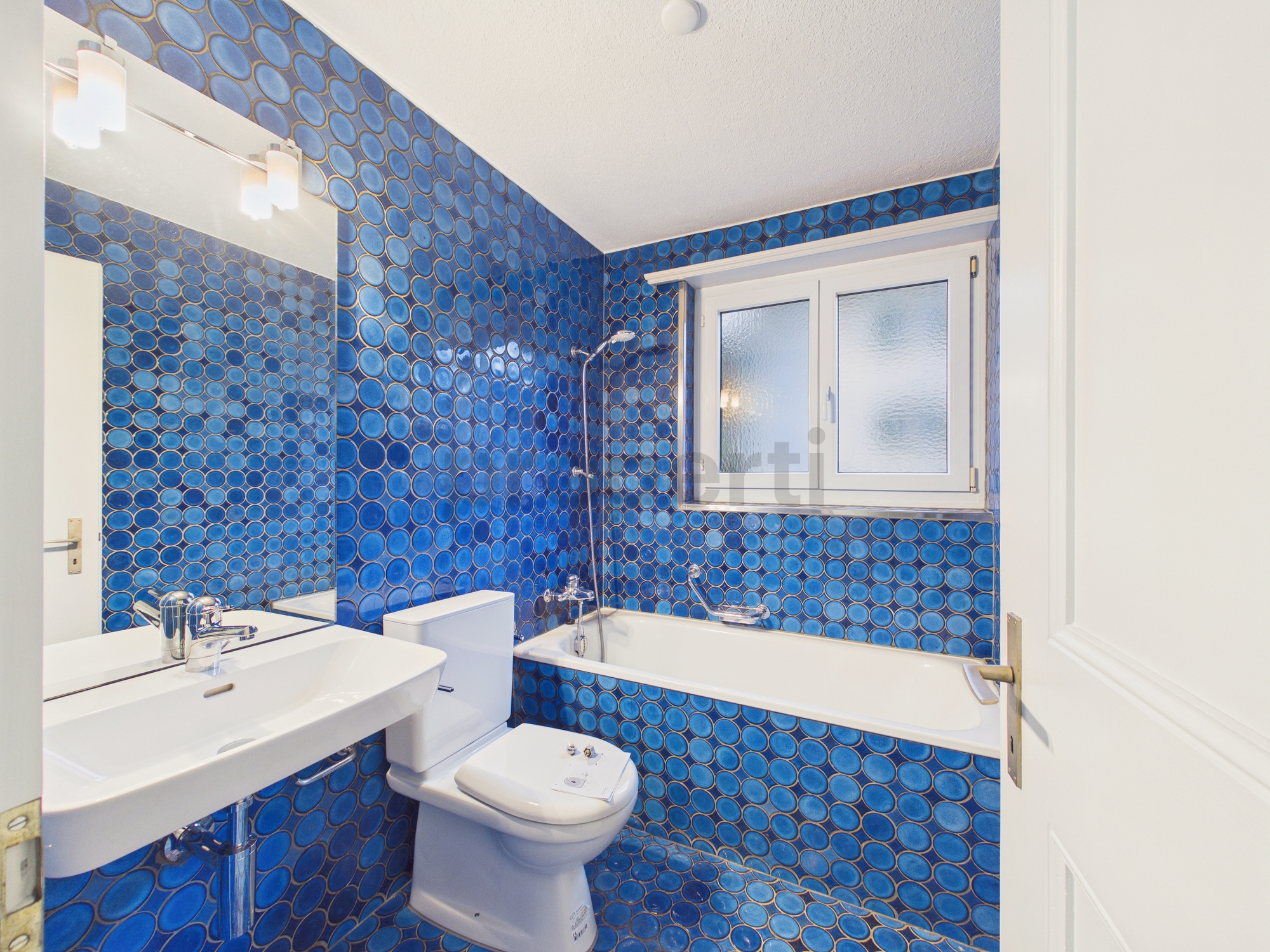 Badezimmer mit blauen Fliesen und Badewanne