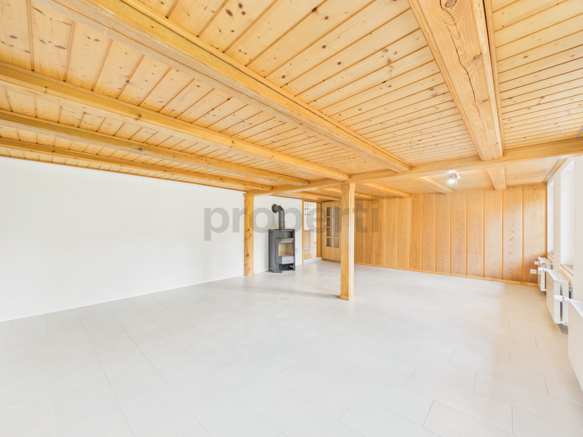 Heller, leerer Wohnraum mit Holzbalkendecke