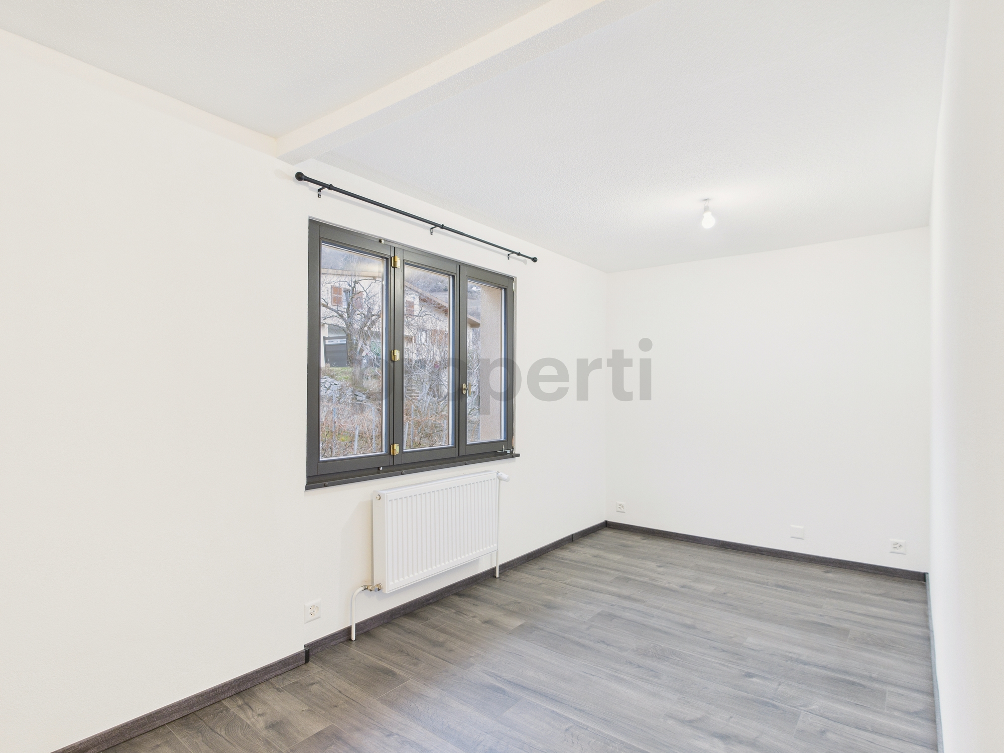 Leeres, renoviertes Zimmer mit Fenster und Heizkörper