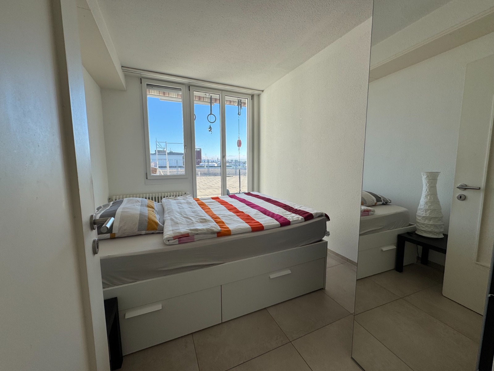 Helles Schlafzimmer mit Fensterfront und Spiegelwand