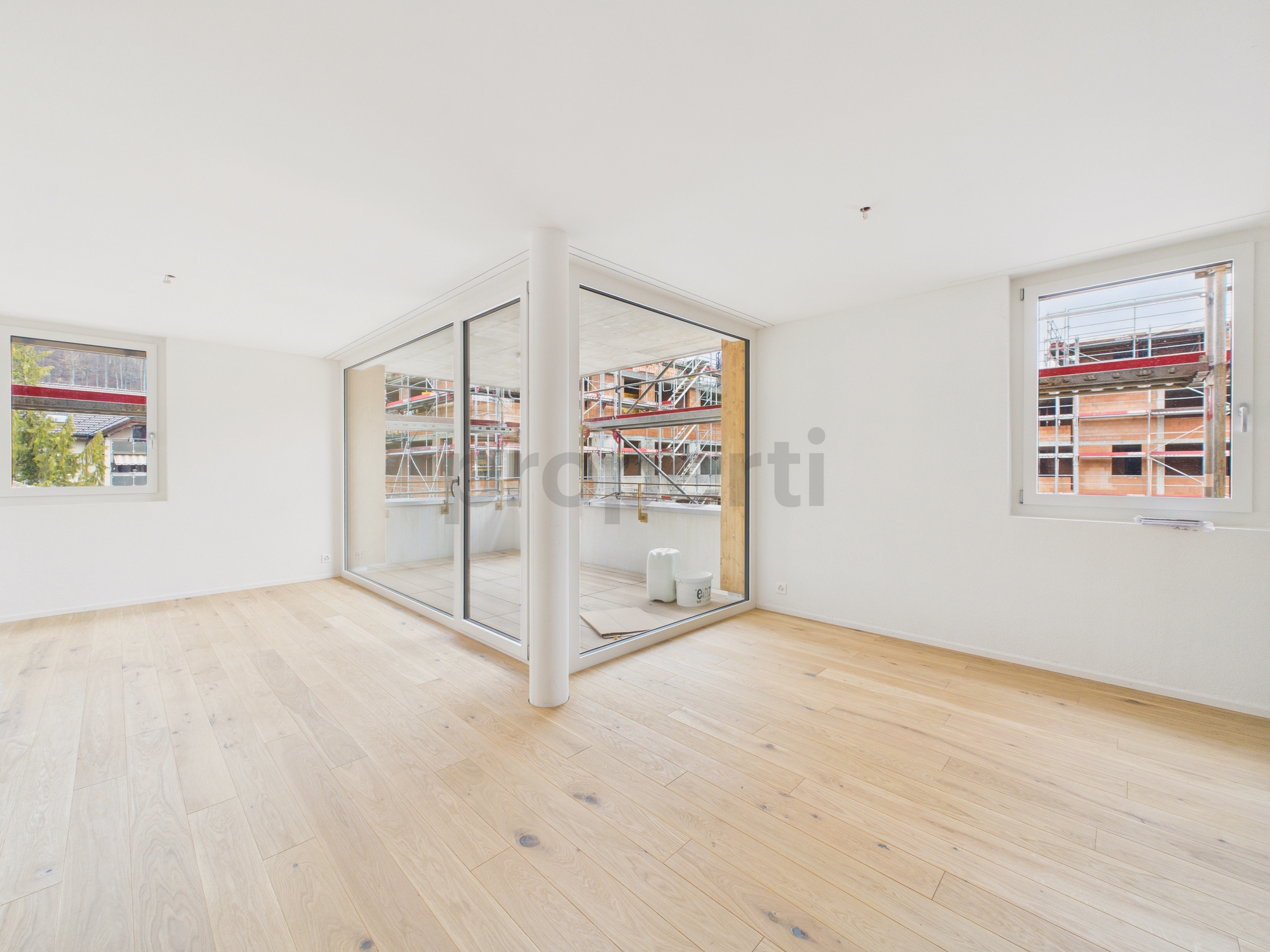 Heller leerer Wohnraum mit Balkon und Blick auf die Baustelle