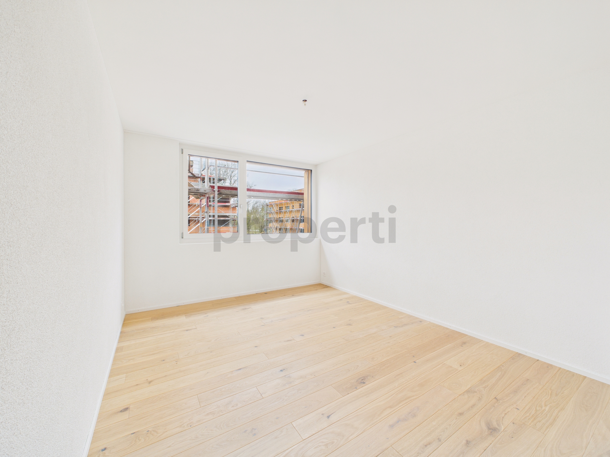 Heller leerer Raum mit Holzboden und Fenster