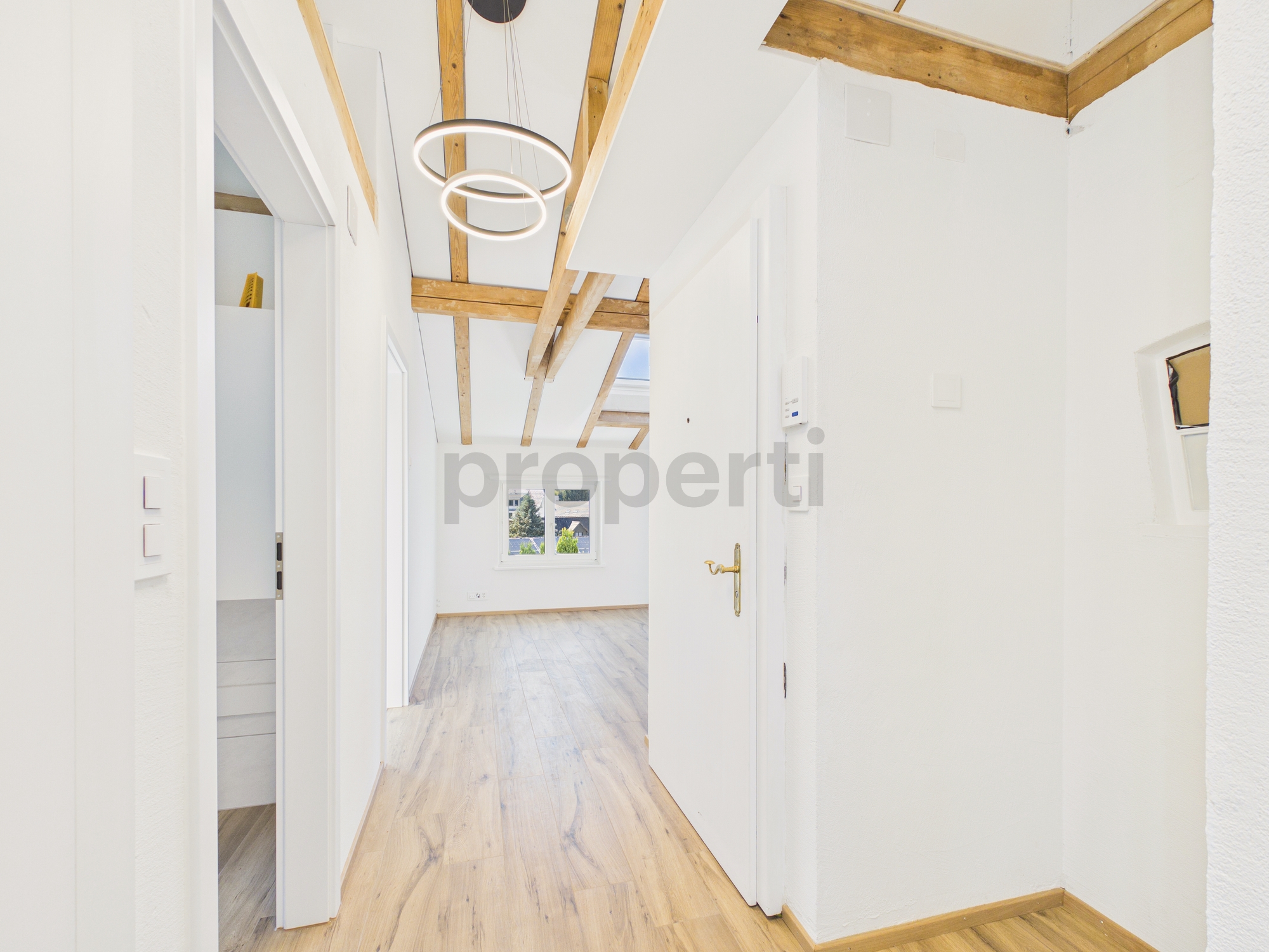 Heller Flur mit sichtbaren Holzbalken und Dachschräge