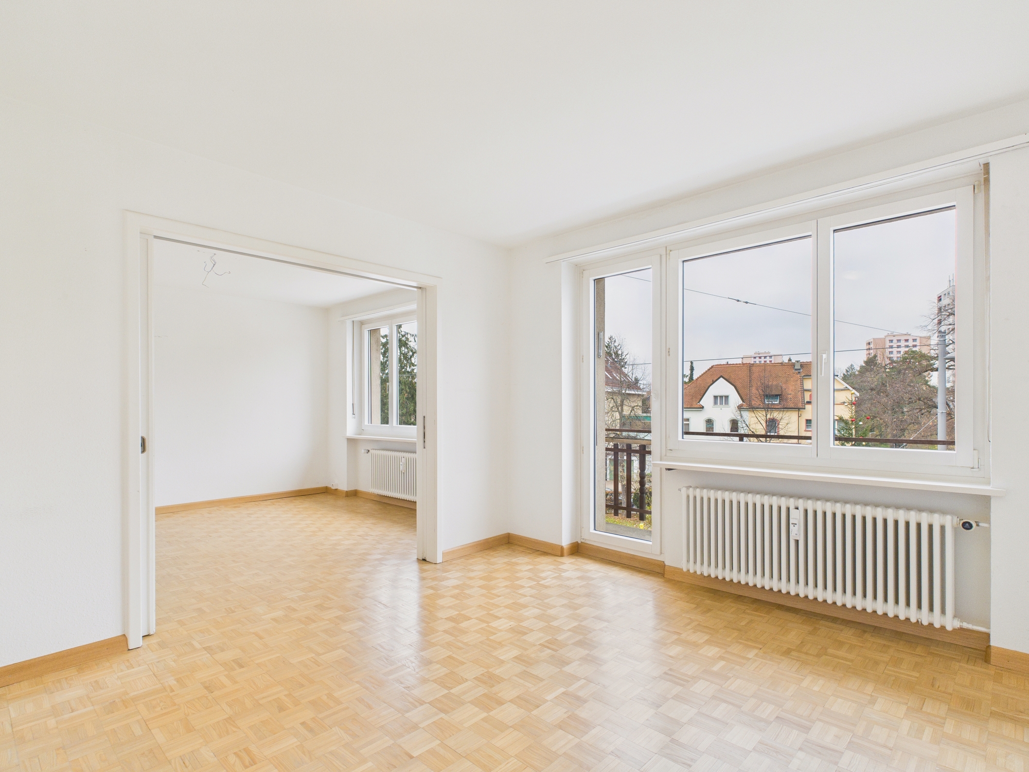Heller leerer Wohnraum mit Parkett und Blick nach draußen