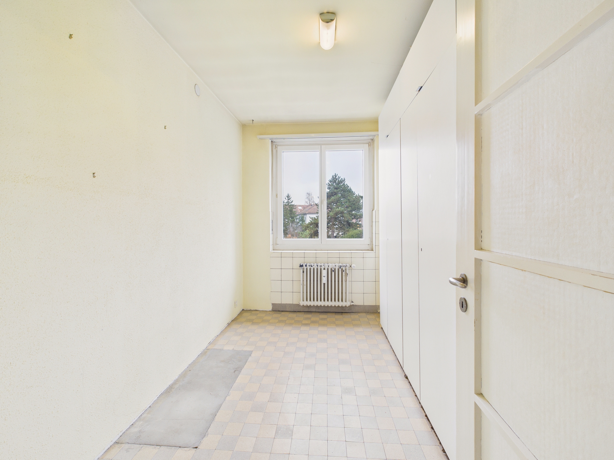 Schmaler Hauswirtschaftsraum mit Fenster und Heizkörper
