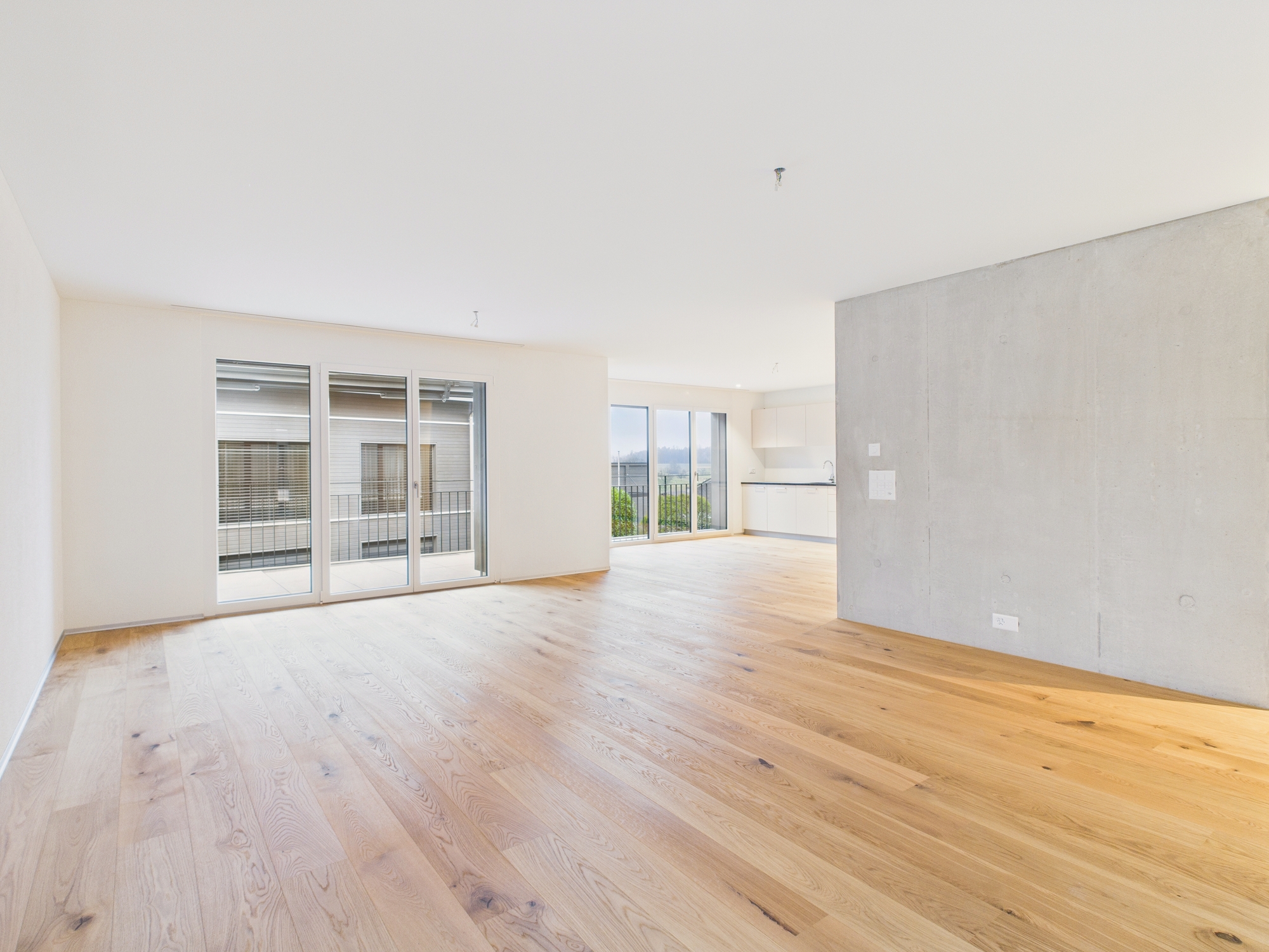 Heller, leerer Wohnbereich mit Balkon und offener Küche
