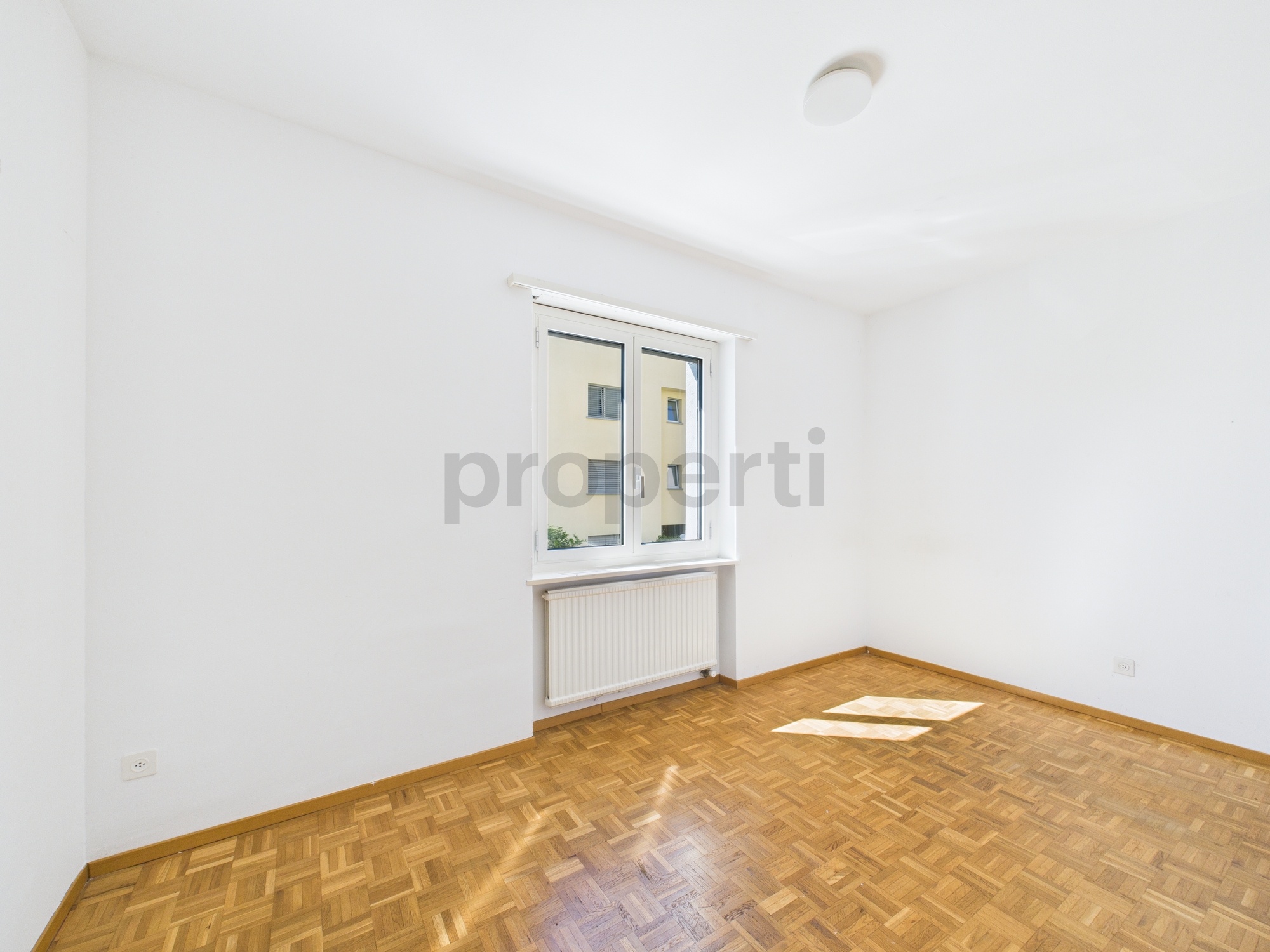 Heller leerer Raum mit Parkettboden und Fenster
