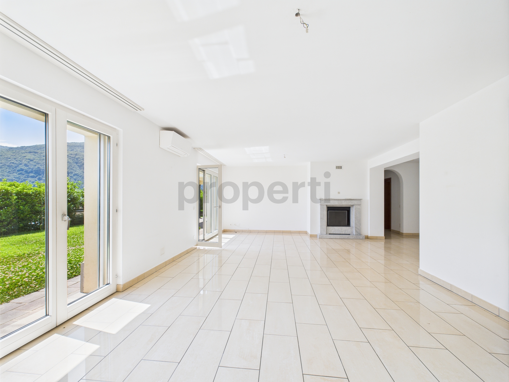 Heller leerer Wohnraum mit Kamin und Gartenblick