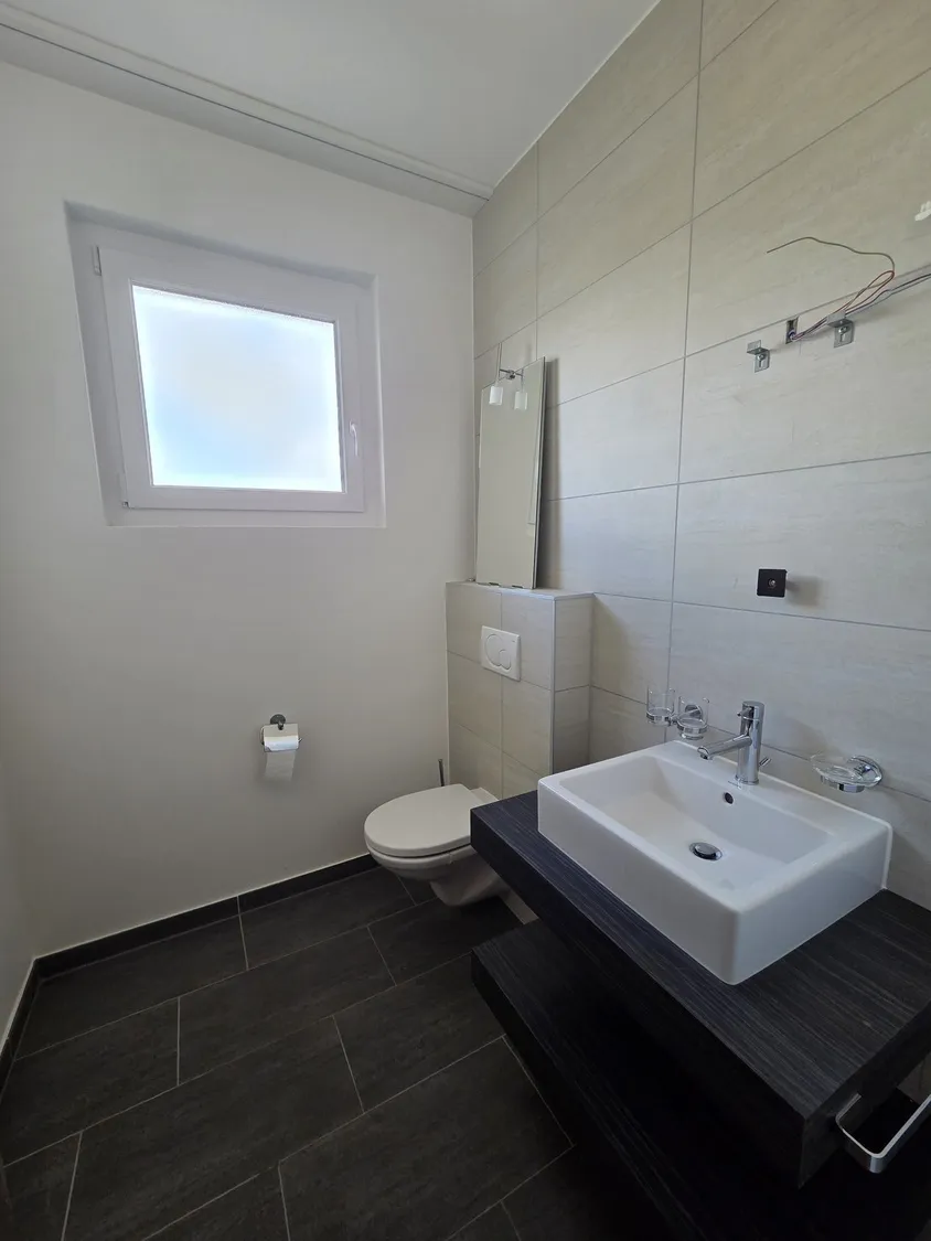 Modernes Gäste-WC mit Fenster und Wand-WC