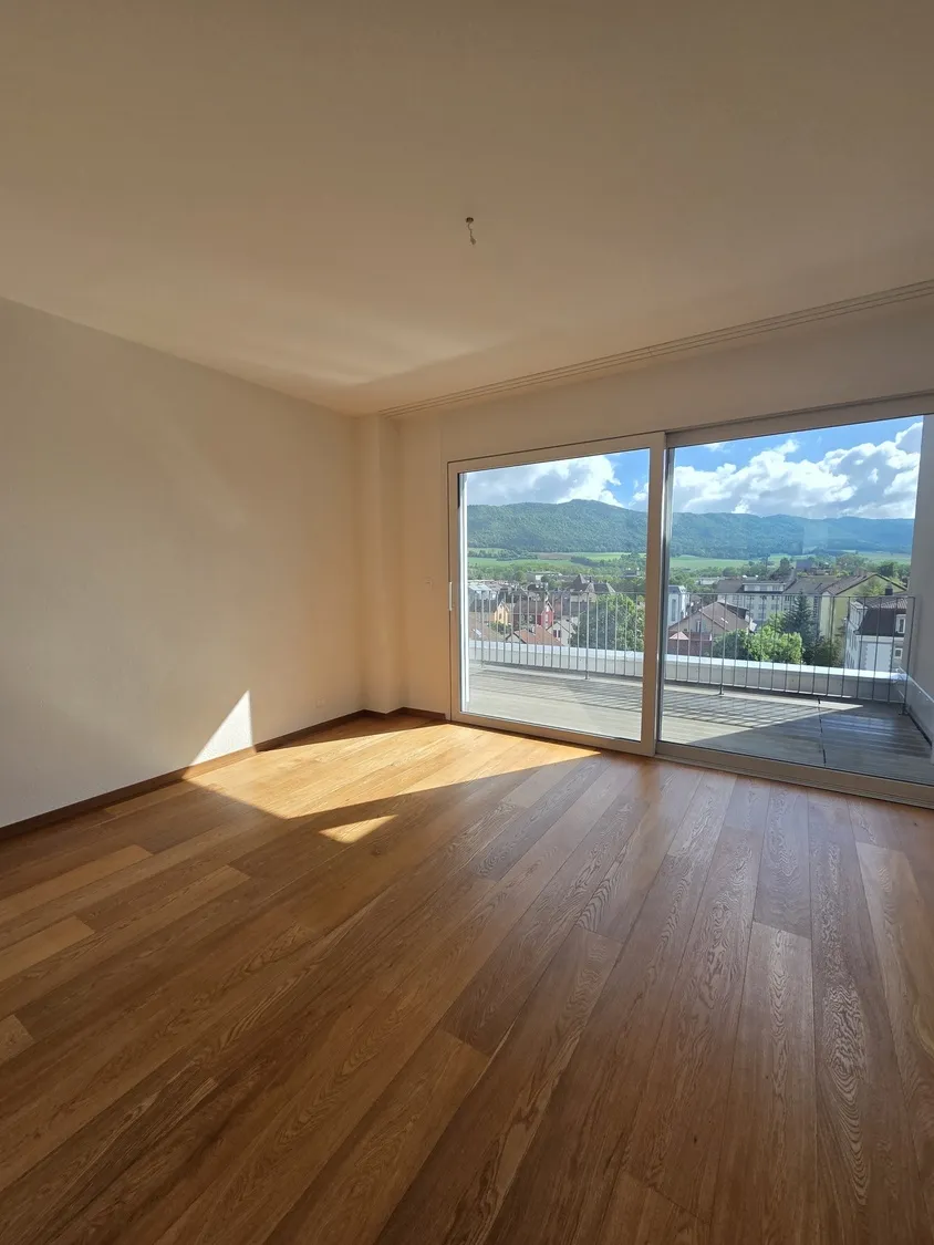 Leerer Wohnraum mit Balkon- und Bergblick