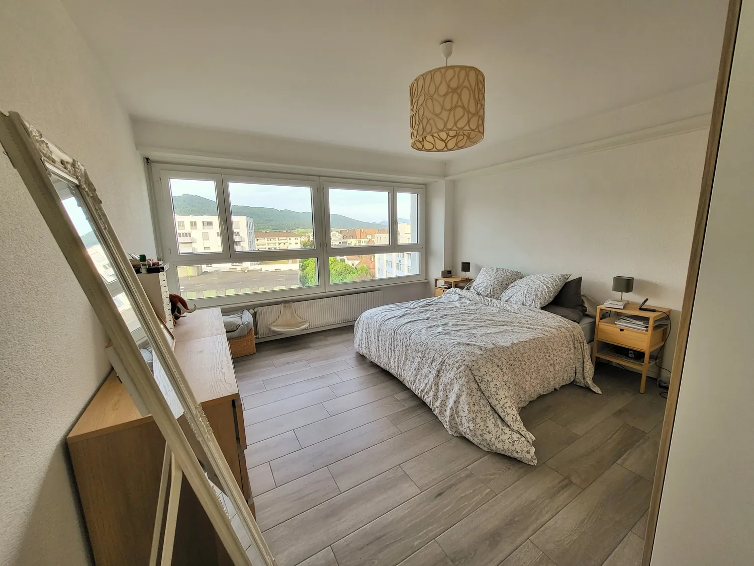 Helles Schlafzimmer mit großem Fenster und Bergblick