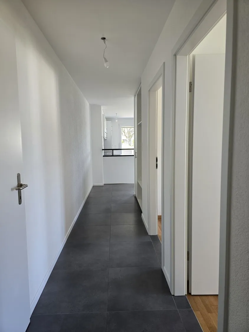Flur mit dunklem Boden und weißen Wänden