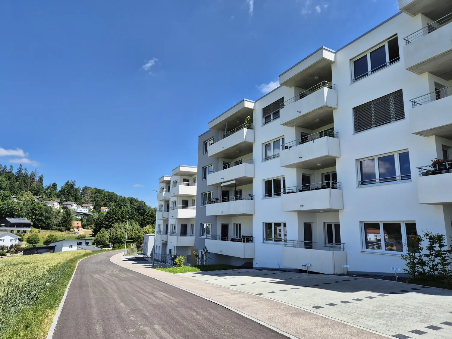 Mehrfamilienhaus mit Balkonen an einer geschwungenen Zufahrt