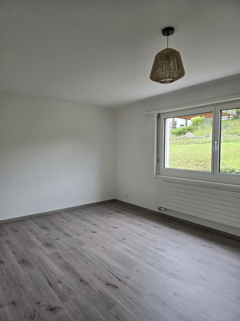 Leeres, helles Zimmer mit Fenster und Heizkörper