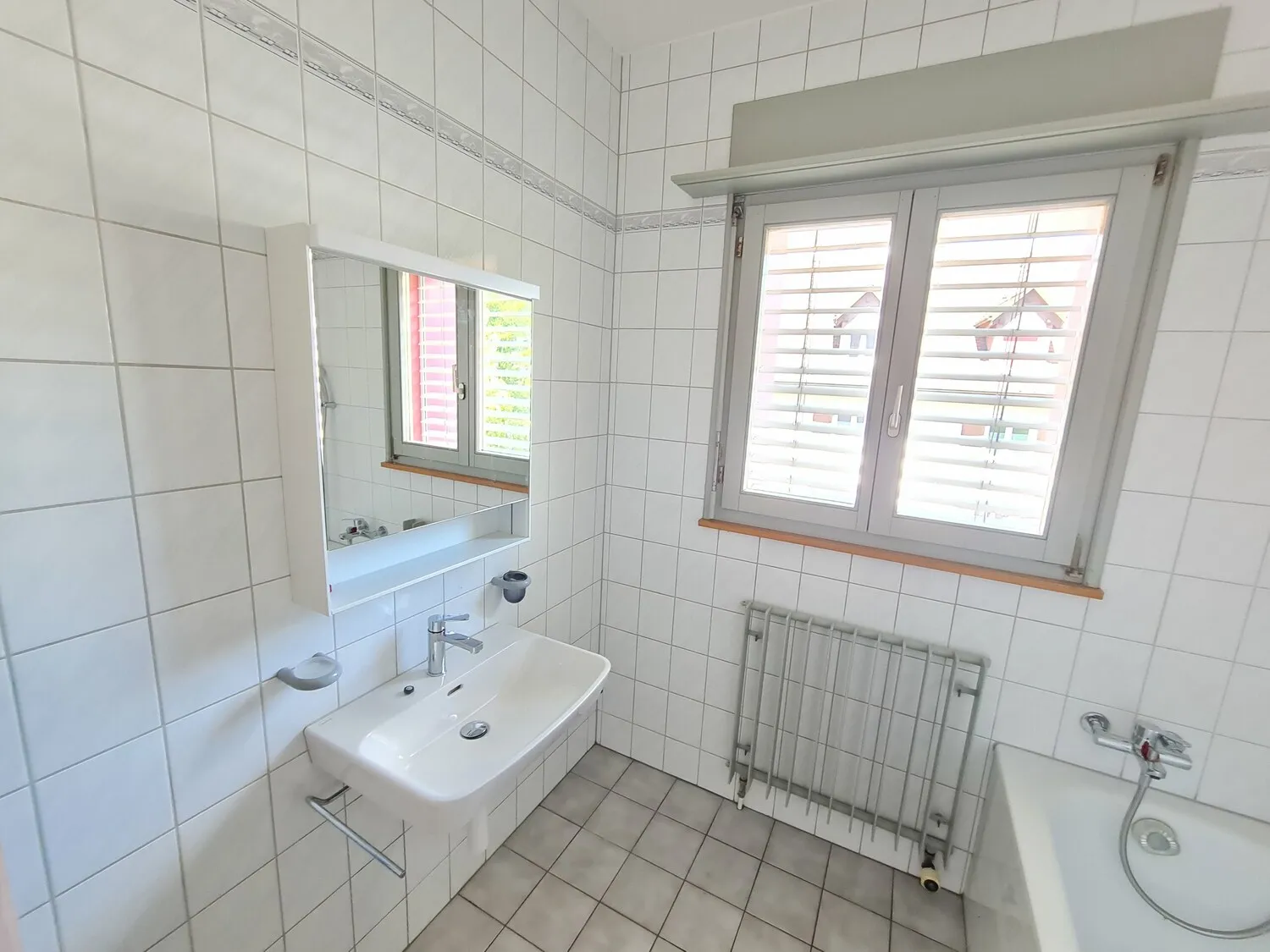Helles Badezimmer mit Fenster, Waschbecken und Badewanne