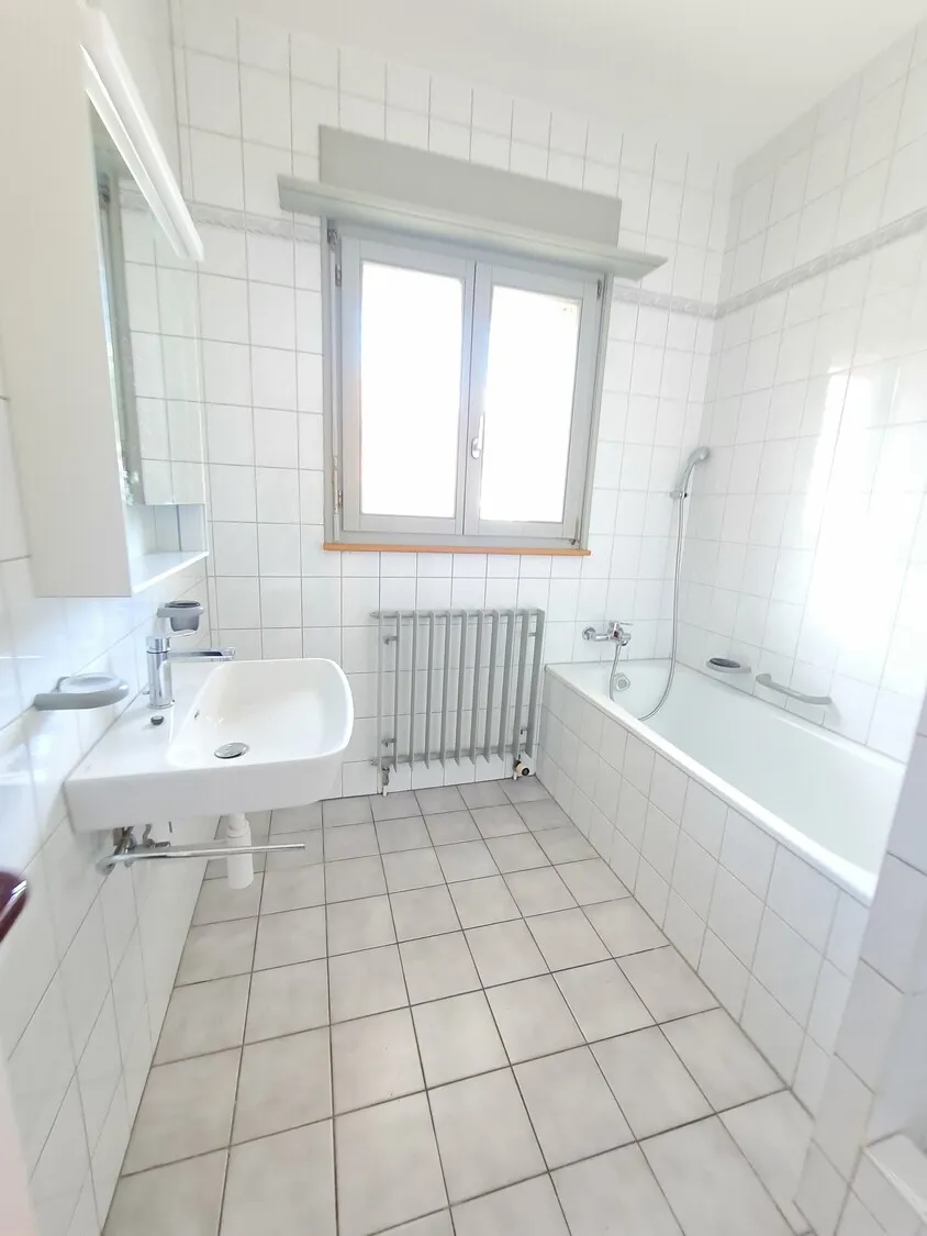 Helles Badezimmer mit Wanne und Fenster