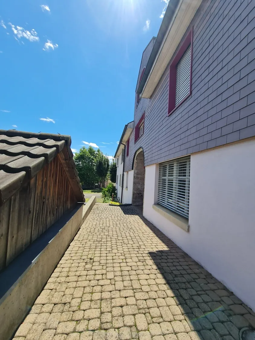 Außenansicht eines Hauses mit gepflastertem Seitenweg