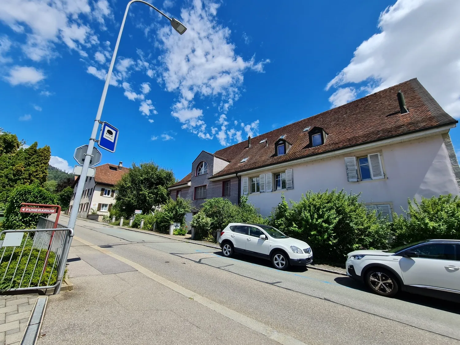 Straßenansicht mit Wohngebäude und parkenden Autos