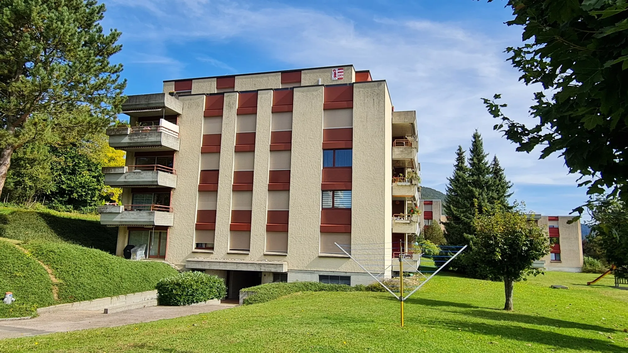 Mehrfamilienhaus mit Balkonen in grüner Hanglage